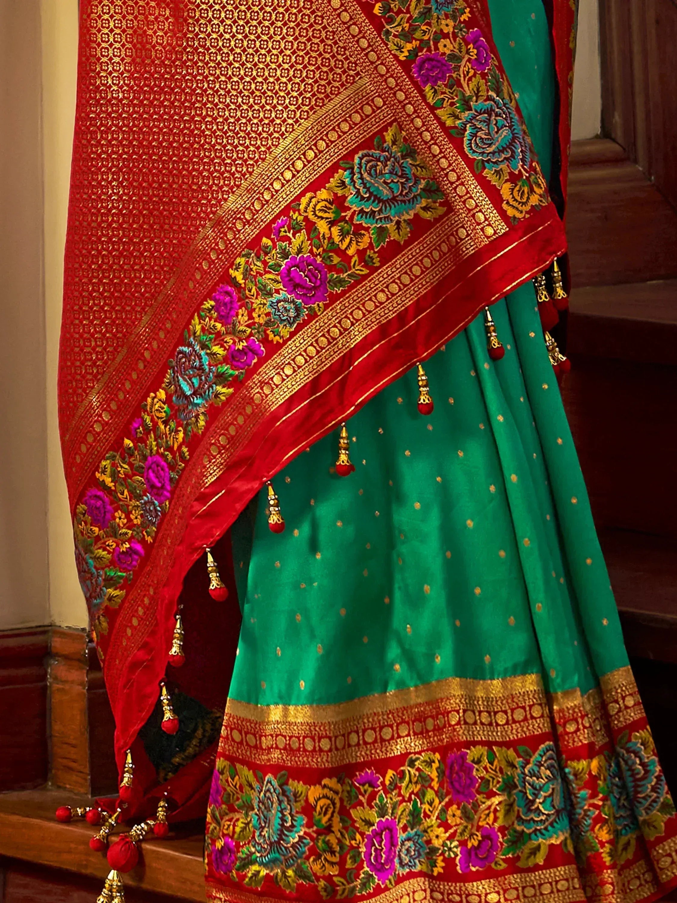 Green and red embroidered lehenga choli with floral border and gold detailing, perfect for Indian ethnic wear.