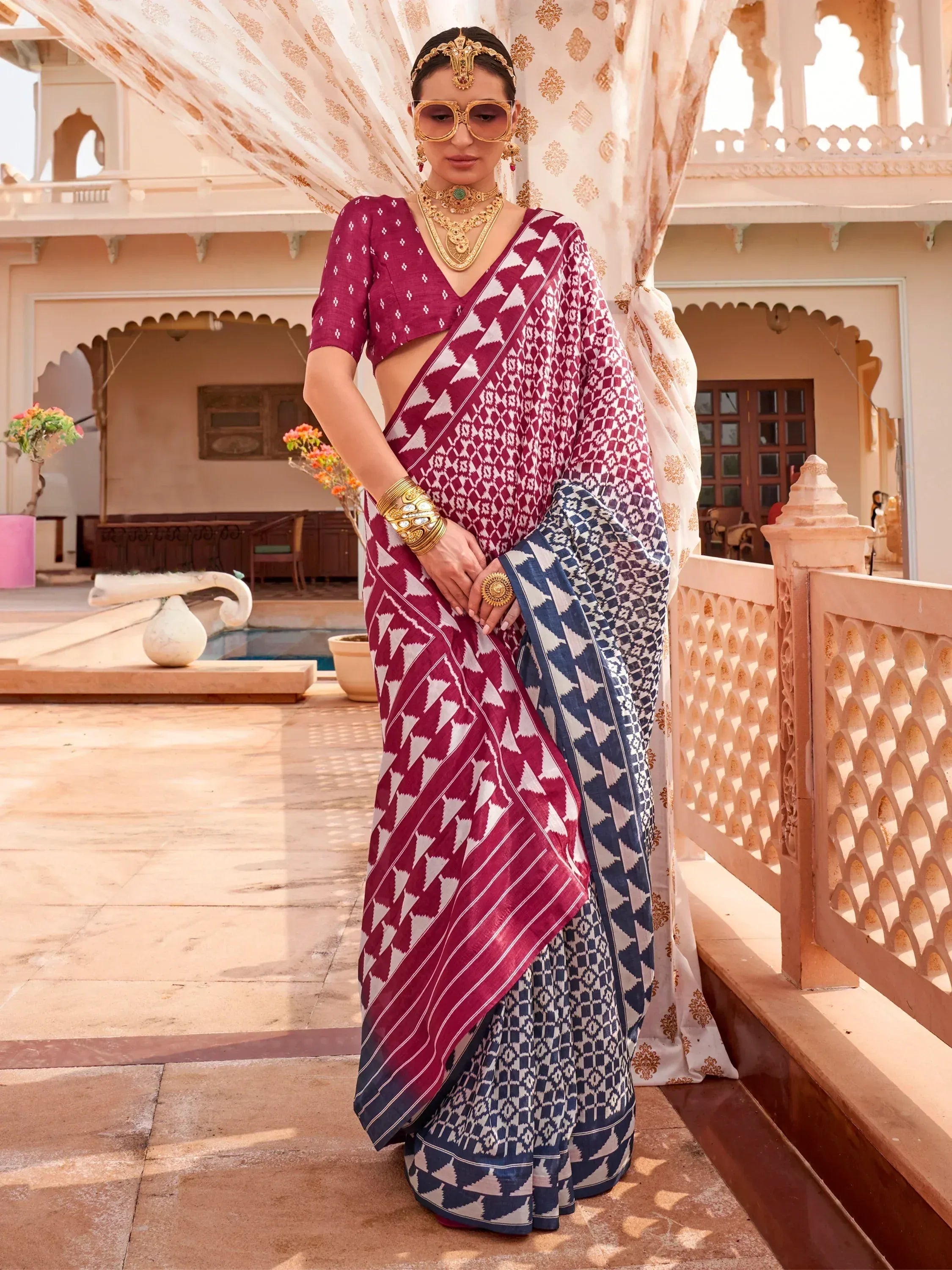 Woman in maroon and blue geometric print saree with gold jewelry, styled for ethnic occasions