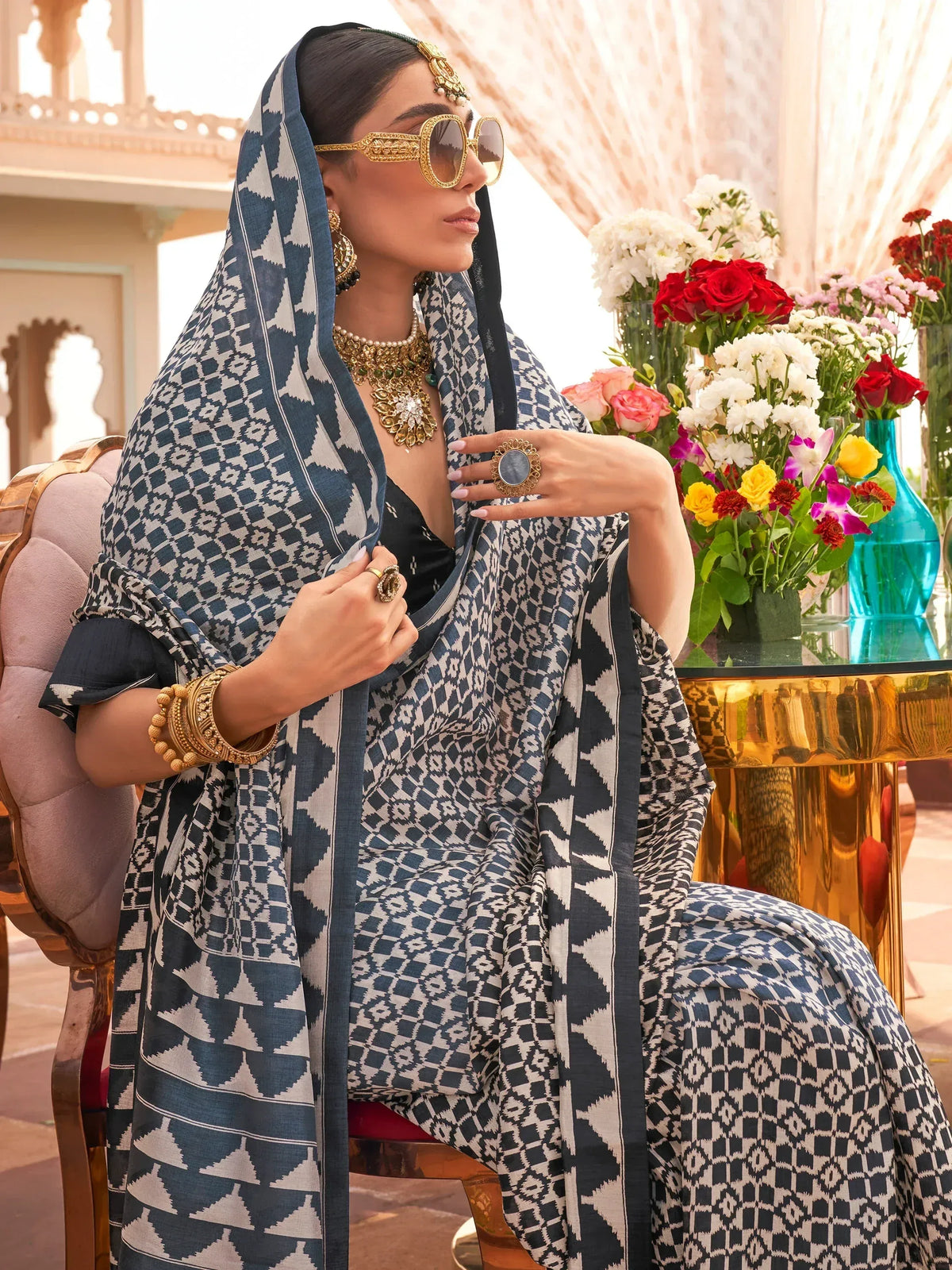 Woman in blue and white geometric print salwar kameez with gold jewelry and sunglasses