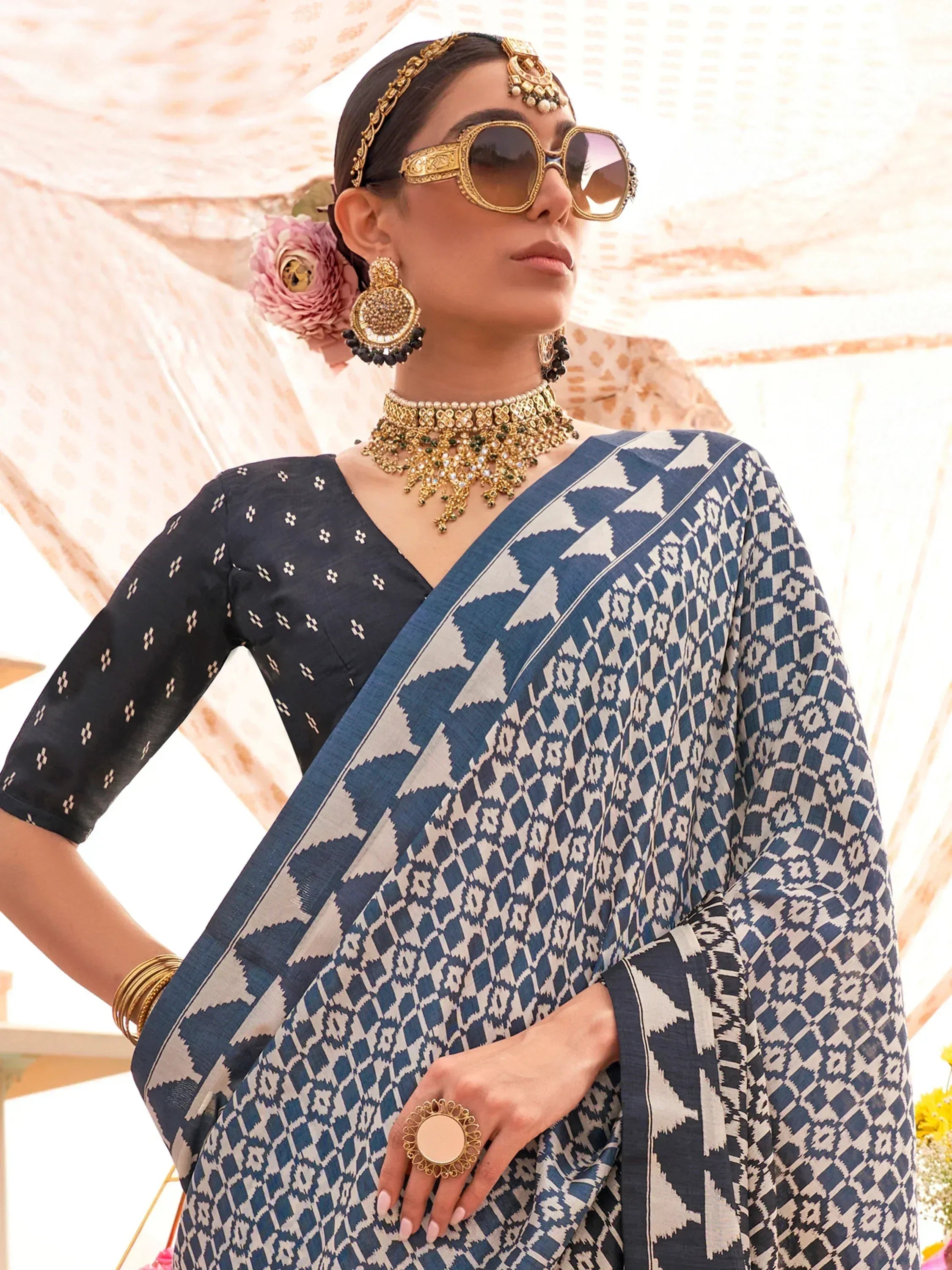 Stylish blue and white ikat saree with black blouse, paired with gold jewelry and sunglasses for ethnic fashion.