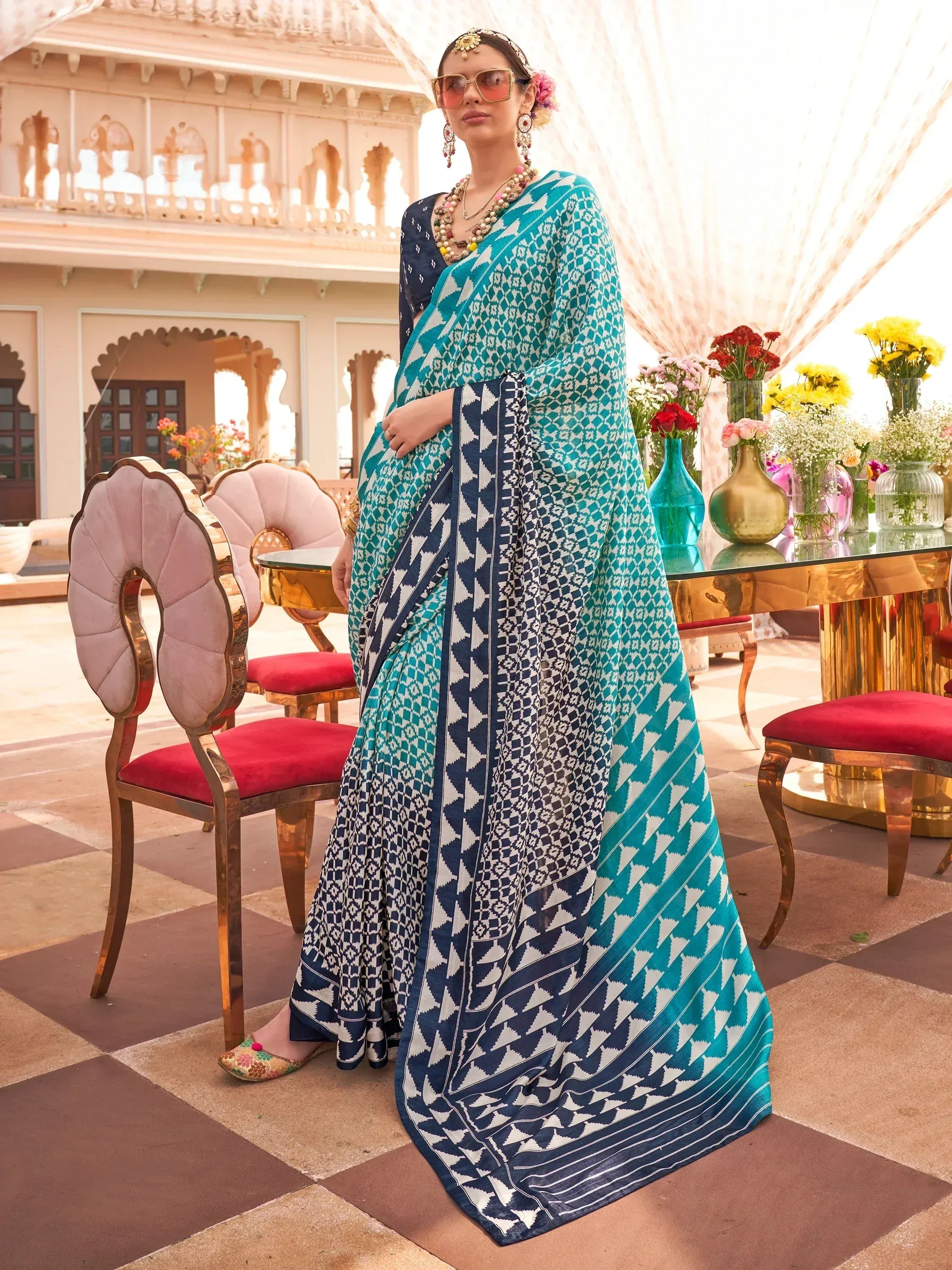 Woman in teal and navy geometric print saree with ethnic jewelry, styled for Indian festive occasions