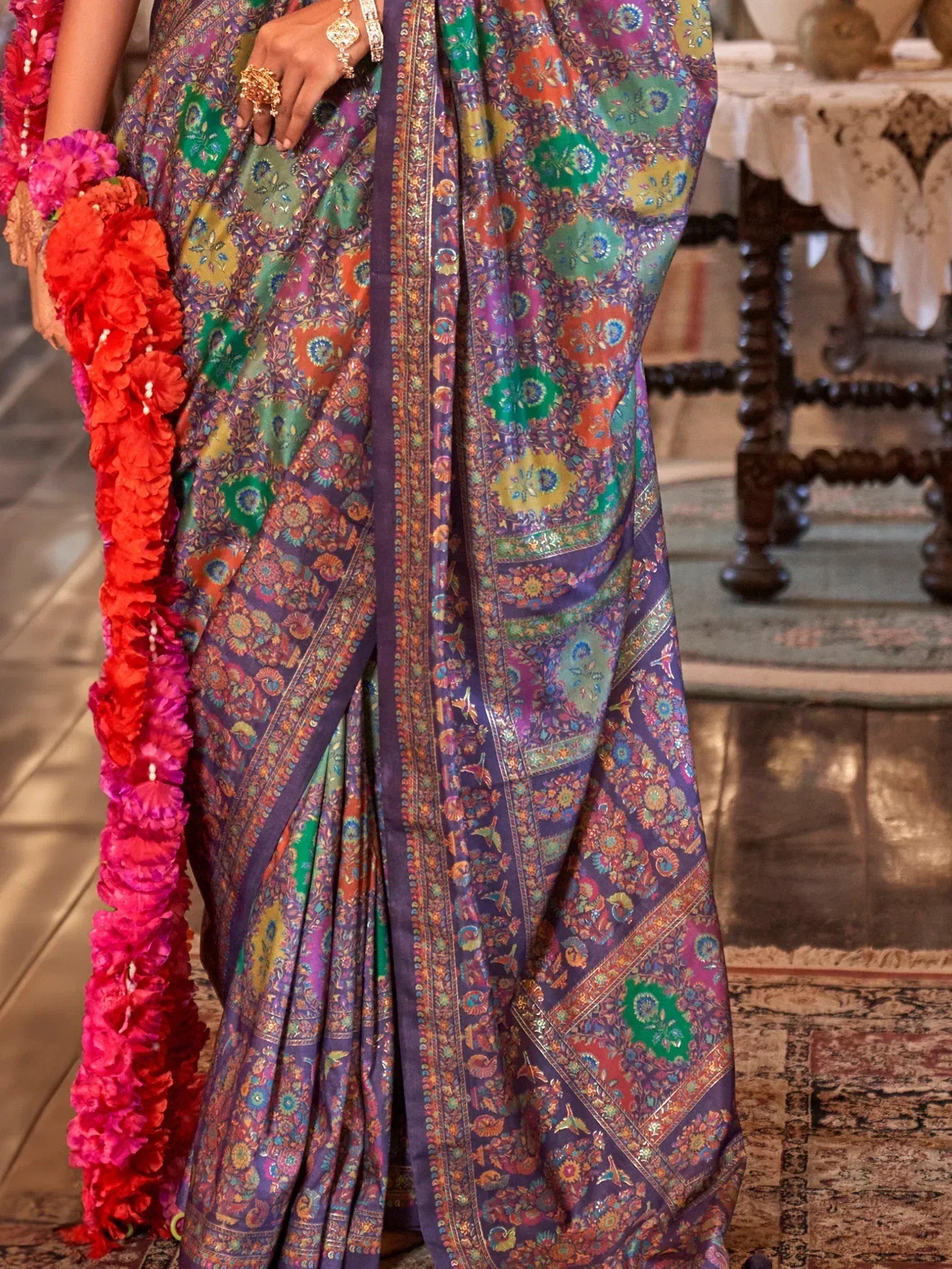 Vibrant floral printed saree with intricate borders, paired with colorful flower garlands