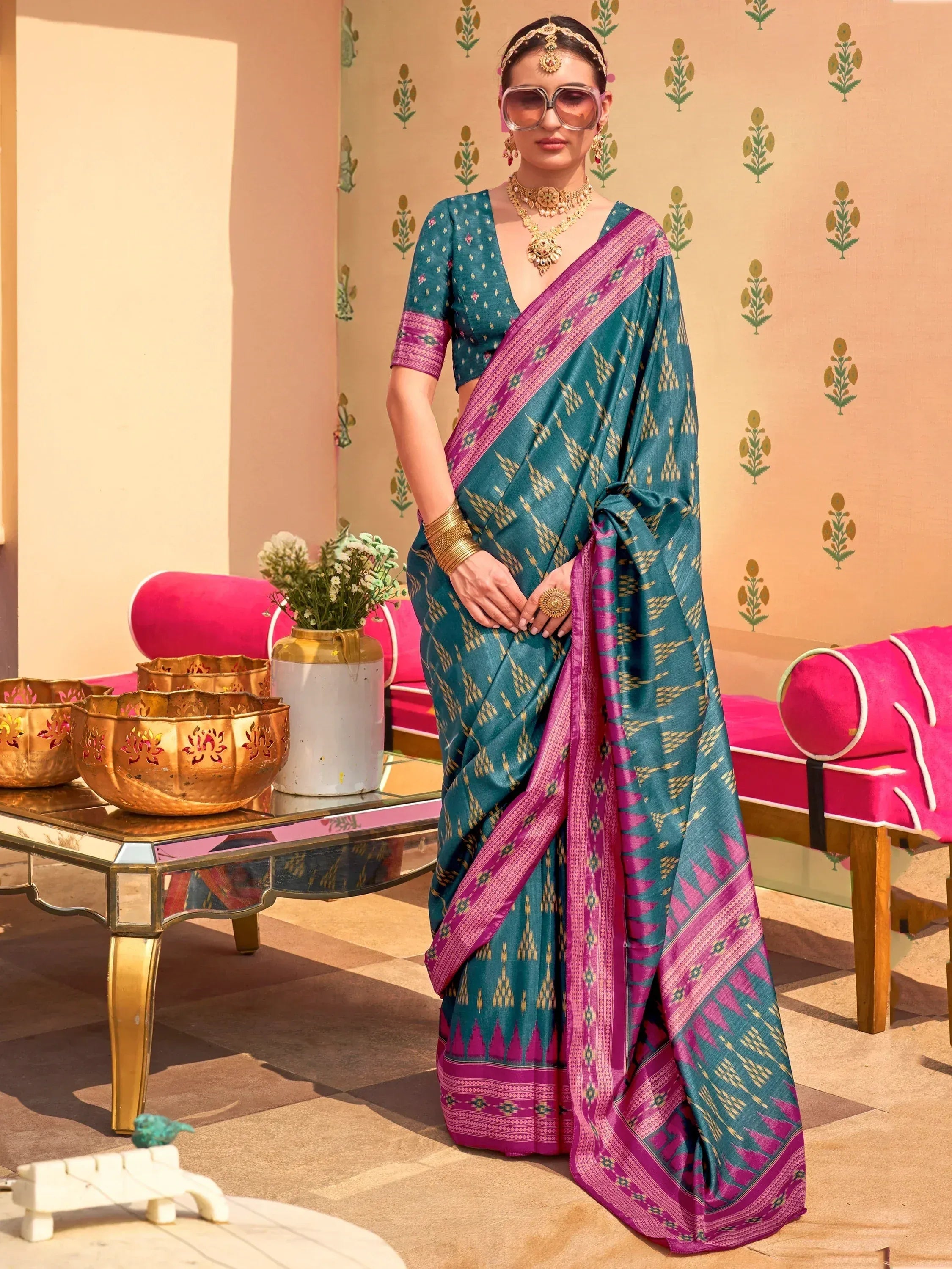 Teal and magenta ikat saree with gold geometric patterns, paired with matching blouse and gold jewelry, styled for festive occasions.