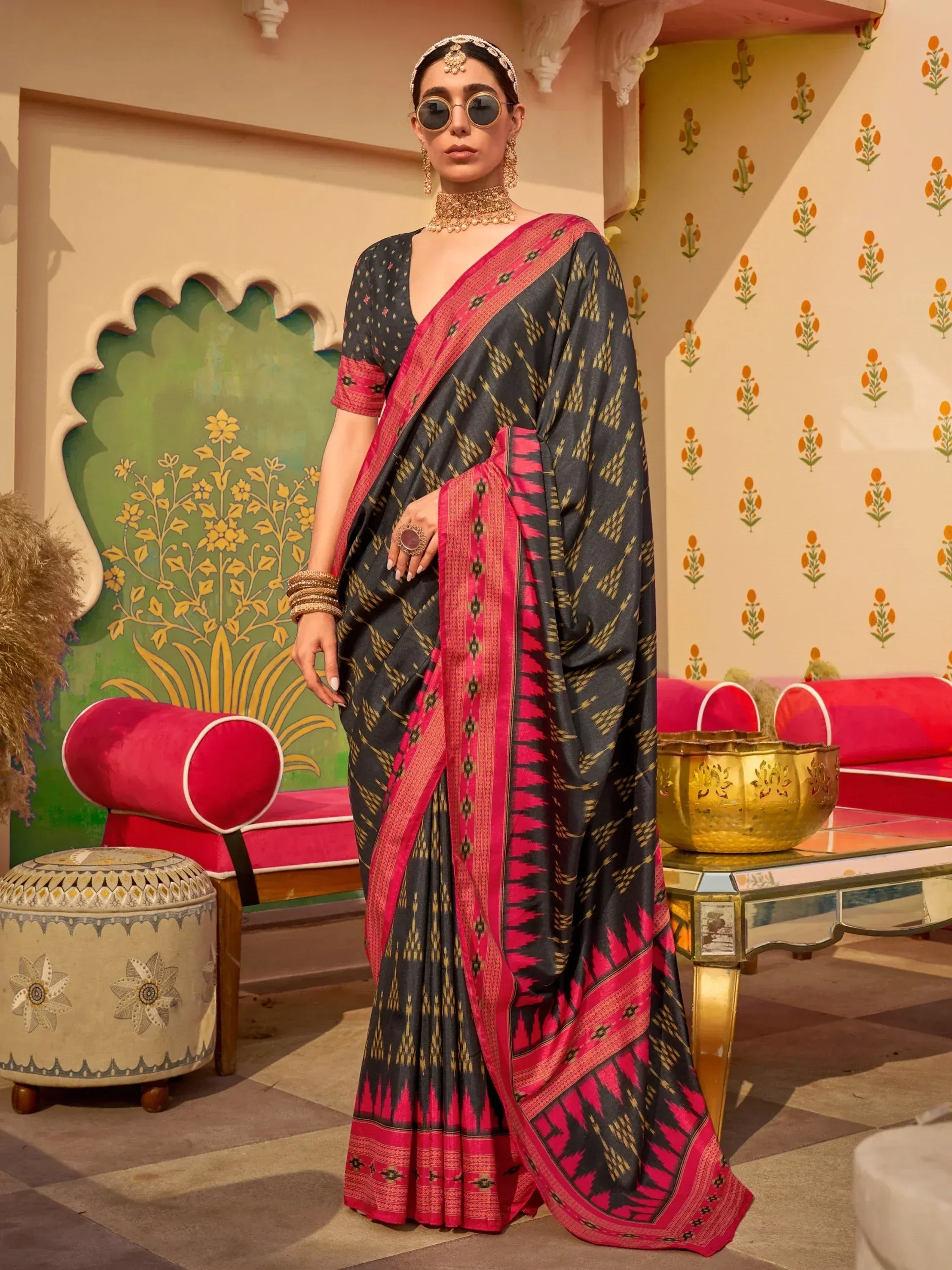 Black and pink ikat saree with gold patterns, styled with traditional jewelry and sunglasses for ethnic wear.