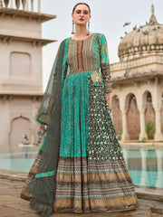 Woman in elegant teal and brown ethnic gown with intricate embroidery, standing by a palace pool