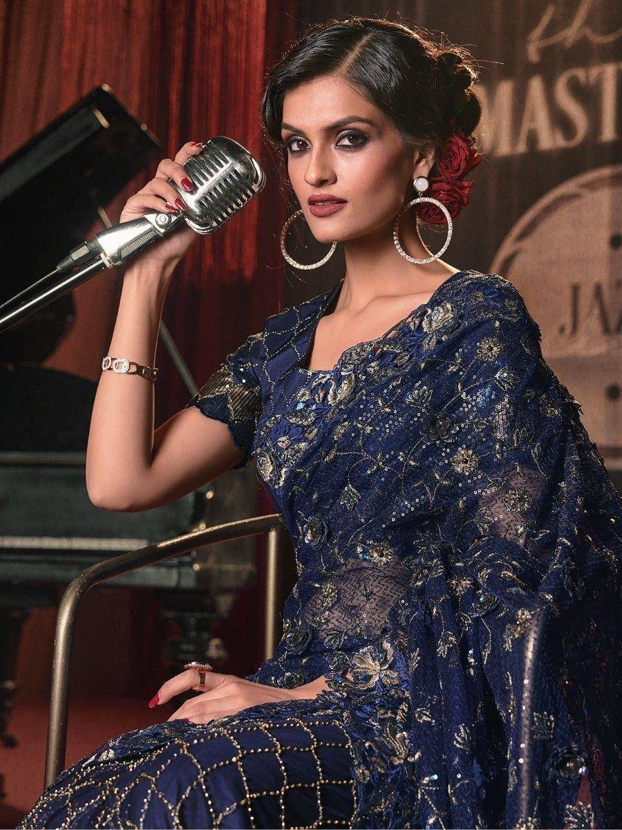 Elegant woman in navy blue embroidered saree with gold detailing, holding vintage microphone, styled for ethnic fashion