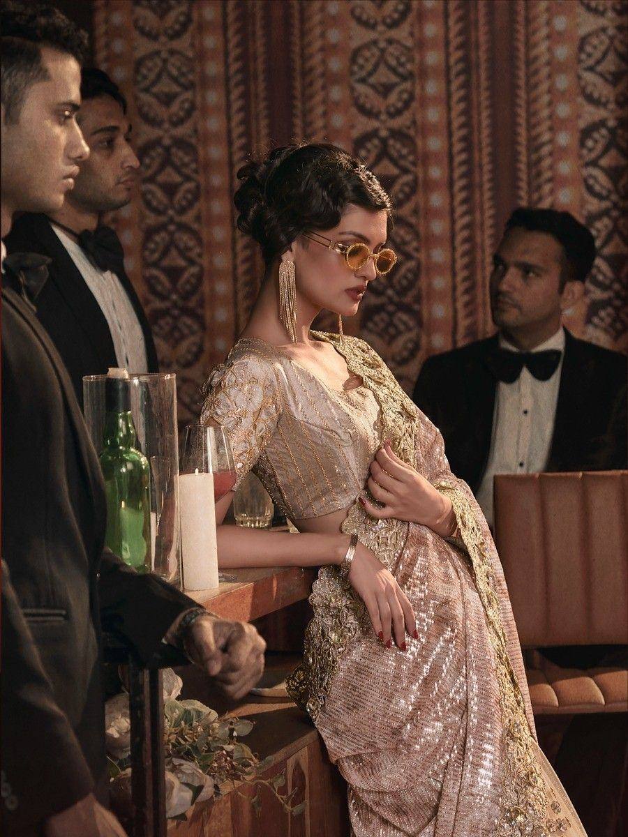 Elegant woman in gold sequin lehenga choli with round sunglasses at a luxury event