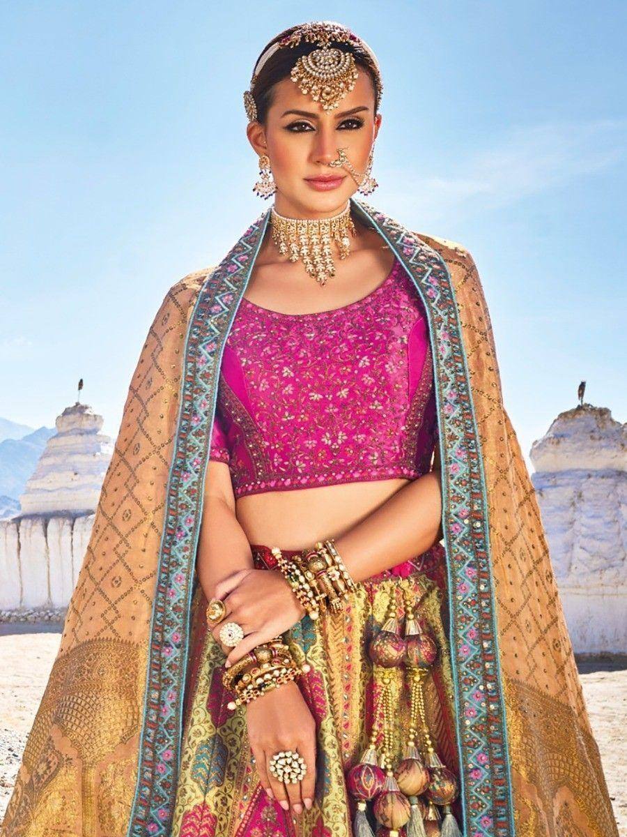 Woman in vibrant pink embroidered lehenga choli with gold dupatta, traditional Indian bridal wear