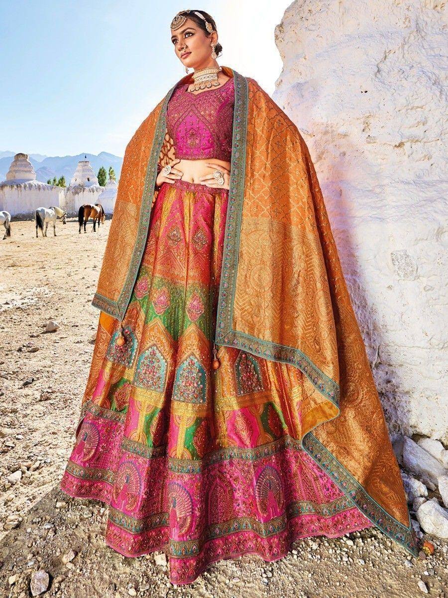 Woman in vibrant pink and orange designer lehenga choli with embroidered dupatta, traditional Indian ethnic wear