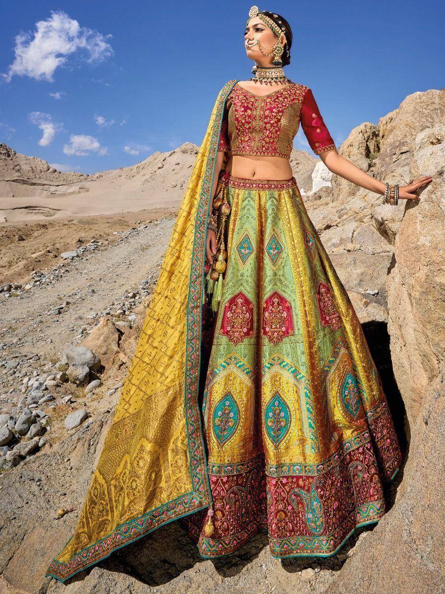 Woman in vibrant designer lehenga choli with intricate embroidery, set against desert landscape