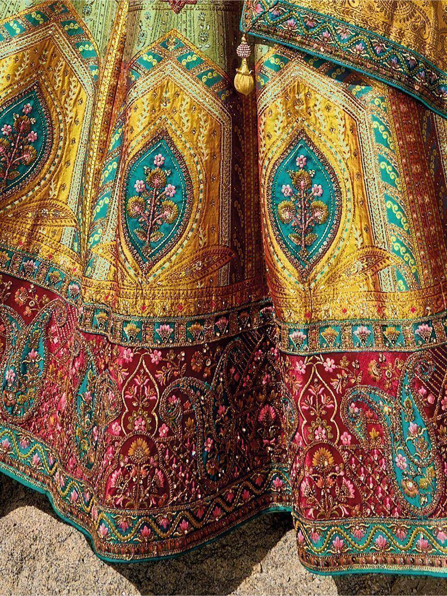 Designer lehenga choli with intricate gold and teal embroidery, floral motifs, and rich maroon border for ethnic wear.