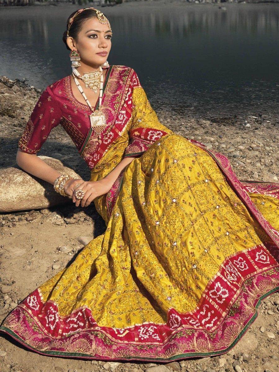 Woman in yellow and maroon embroidered lehenga choli by water, traditional Indian ethnic wear