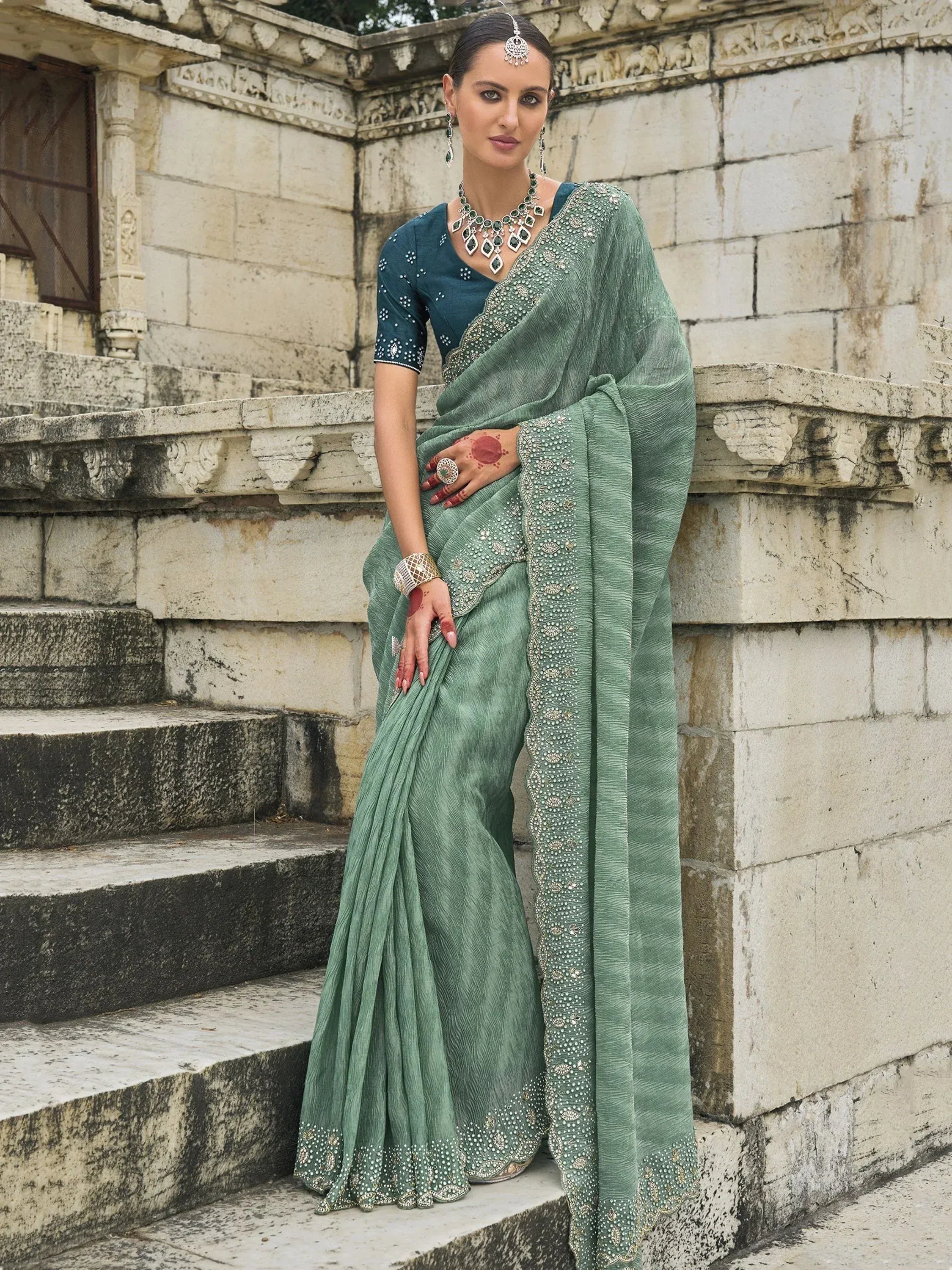 Elegant green saree with intricate embroidery, paired with a teal blouse, perfect for Indian ethnic occasions.