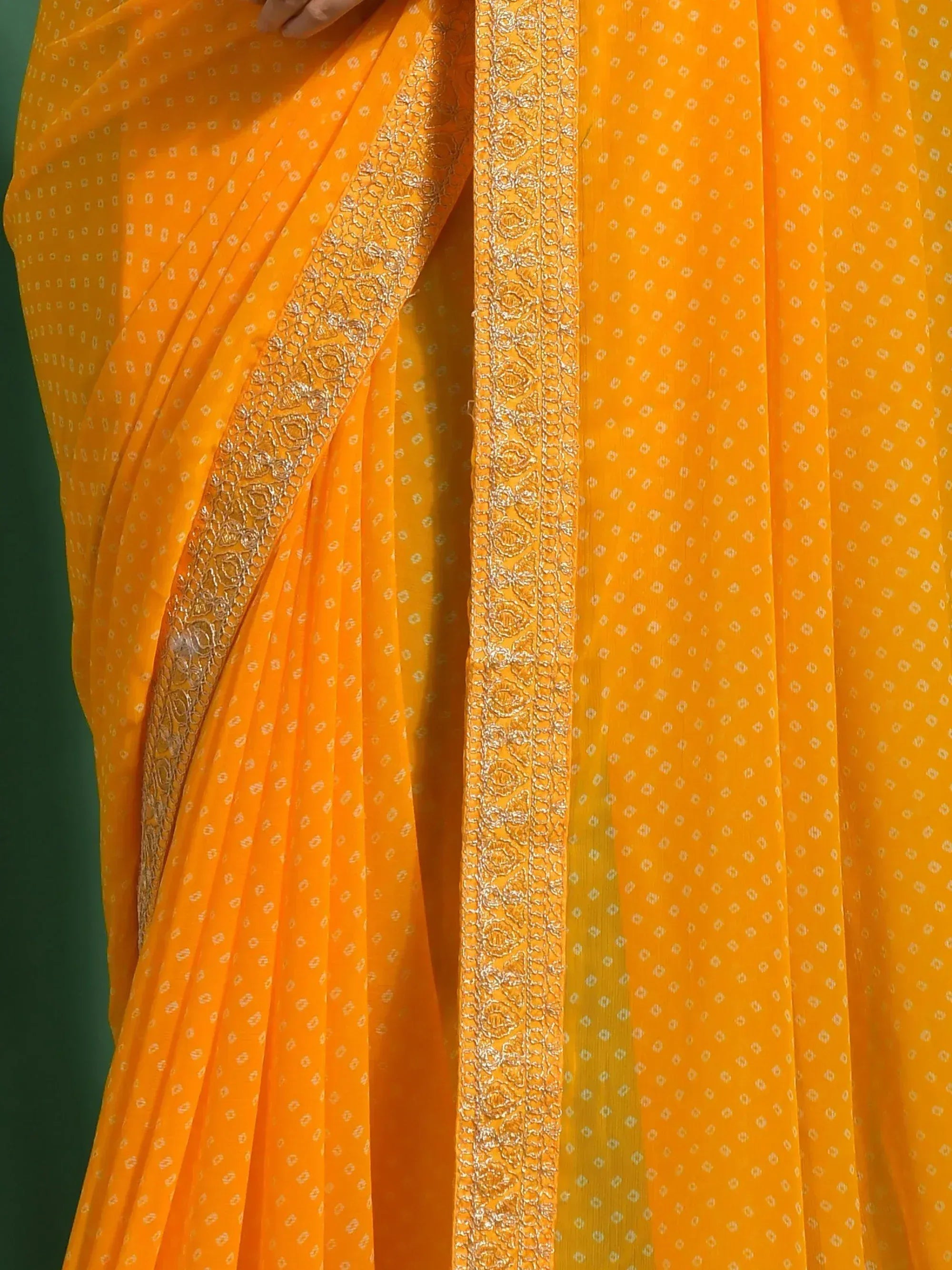 Vibrant orange saree with delicate white motifs and intricate gold border, perfect for ethnic occasions.