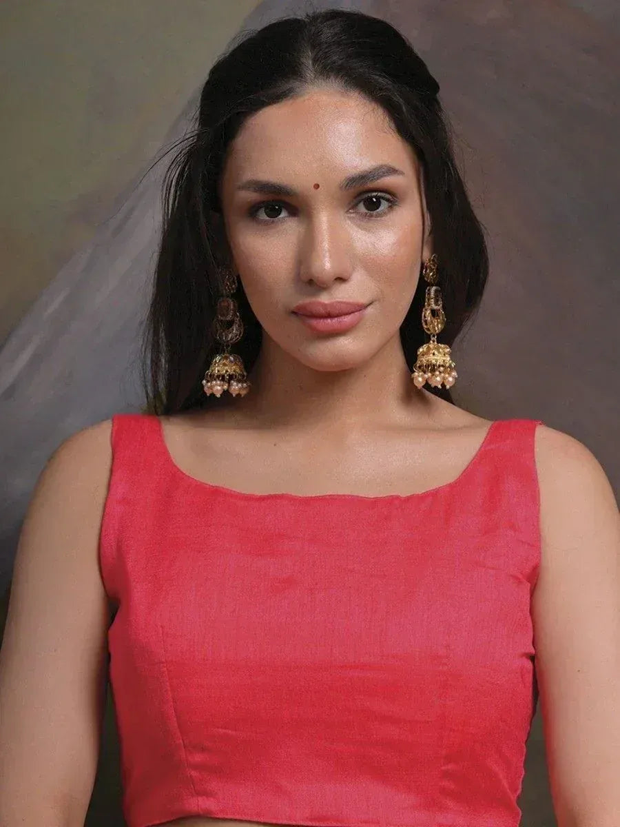 Woman in coral pink sleeveless blouse with gold jhumka earrings, Indian ethnic wear