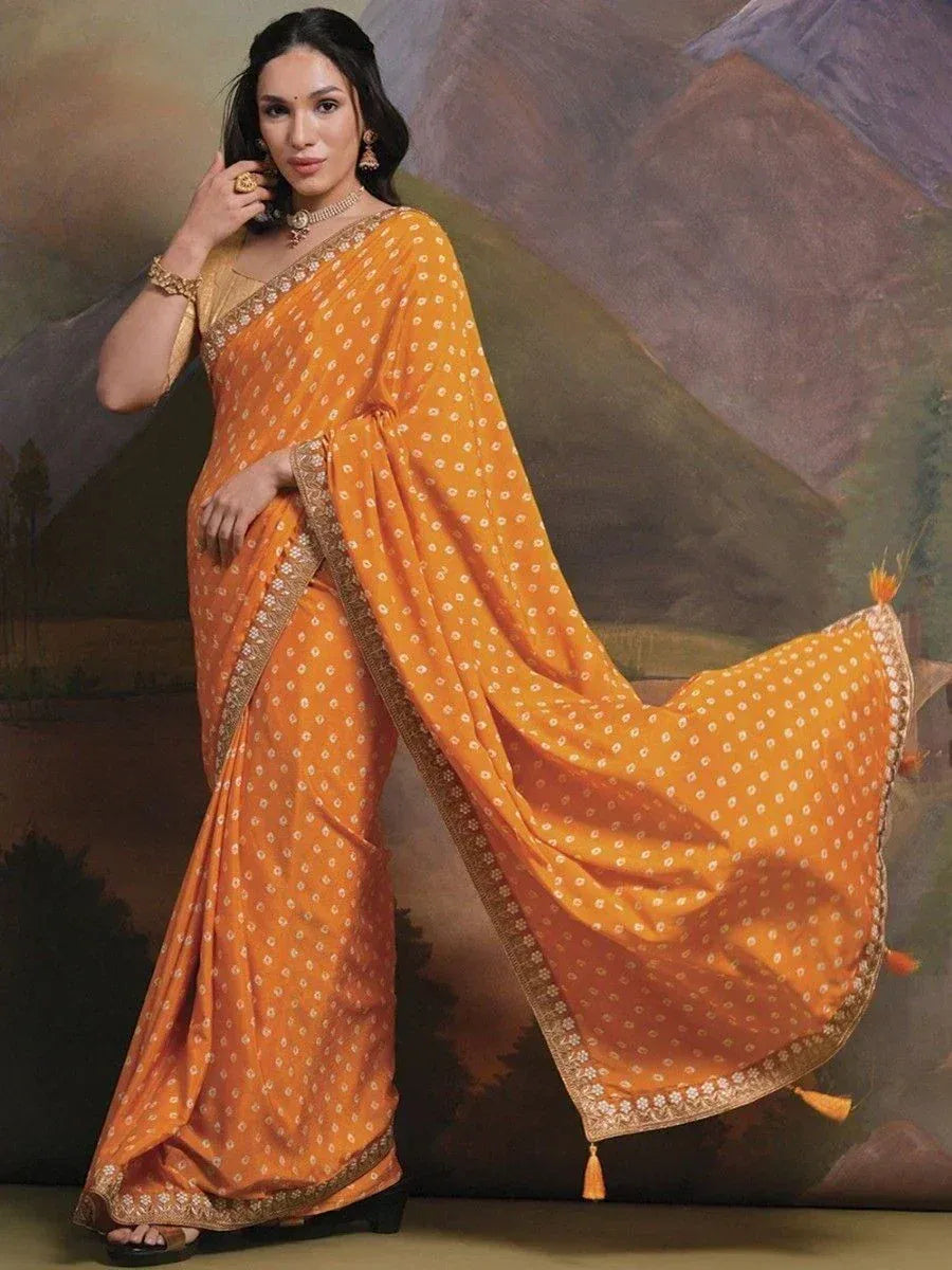 Orange printed saree with gold border and tassels, styled with ethnic jewelry for traditional occasions