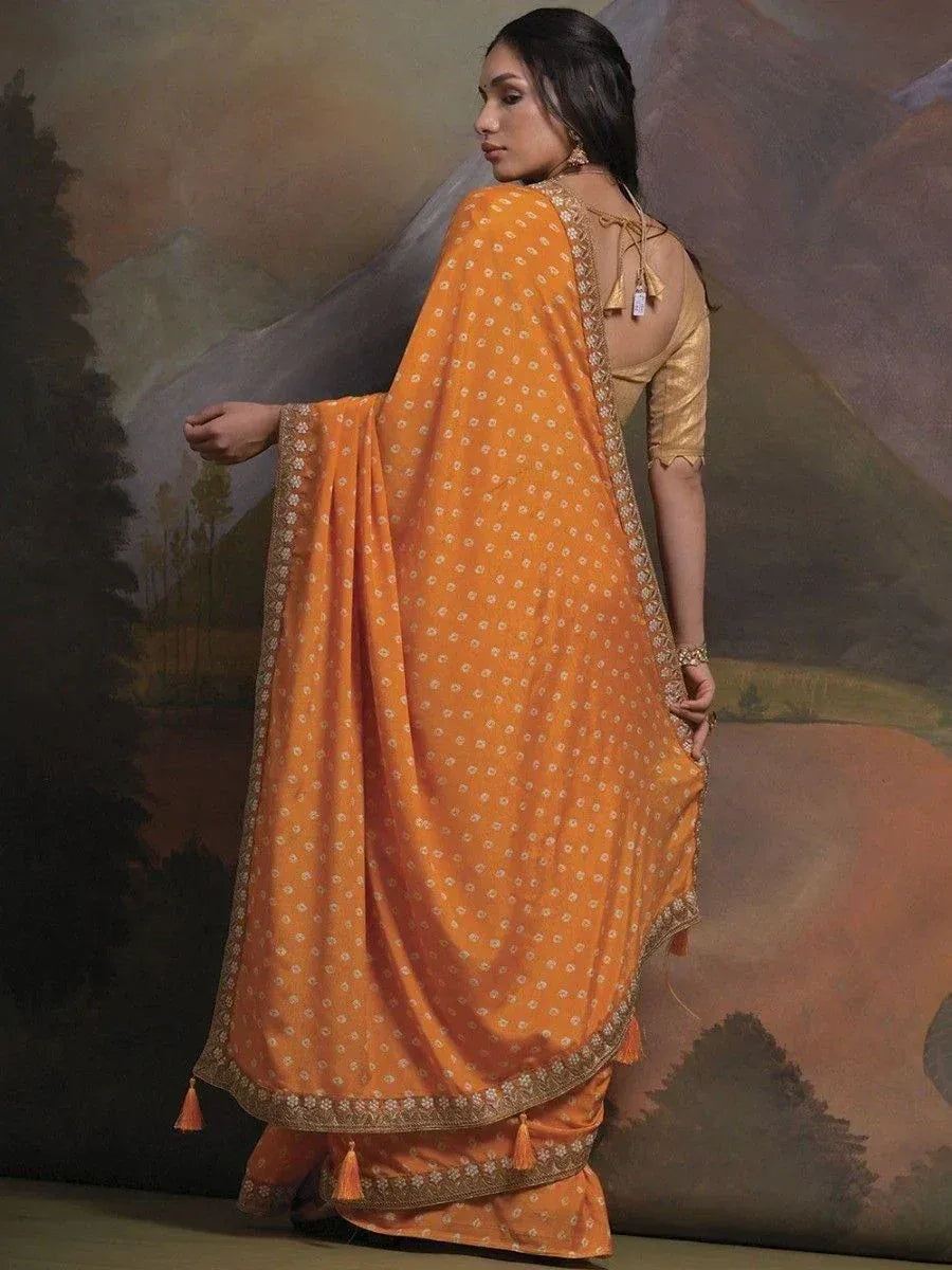 Orange printed saree with gold border and tassels, paired with designer blouse for ethnic wear