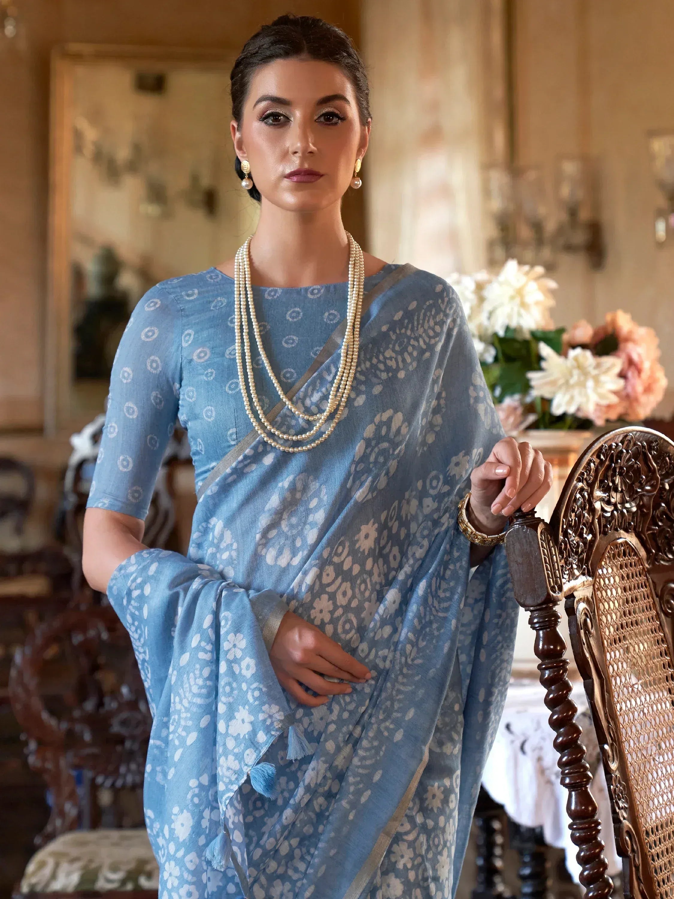 Elegant blue printed saree with floral motifs, paired with pearl jewelry for traditional Indian ethnic wear