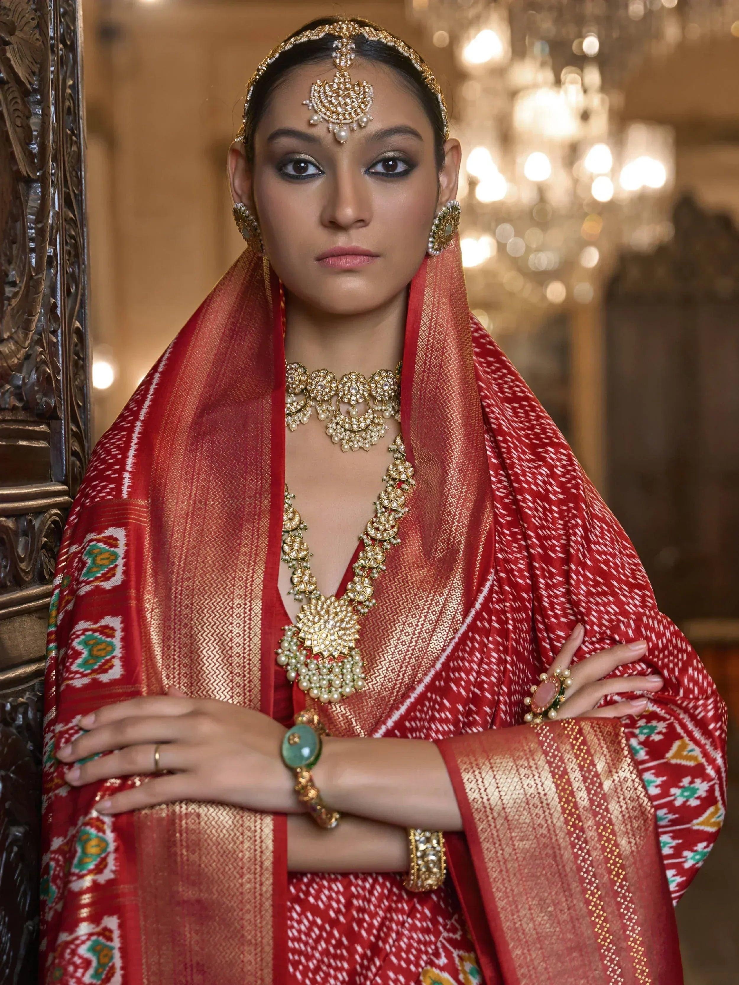 Woman in red ethnic saree with gold jewelry and traditional headpiece, elegant Indian wear