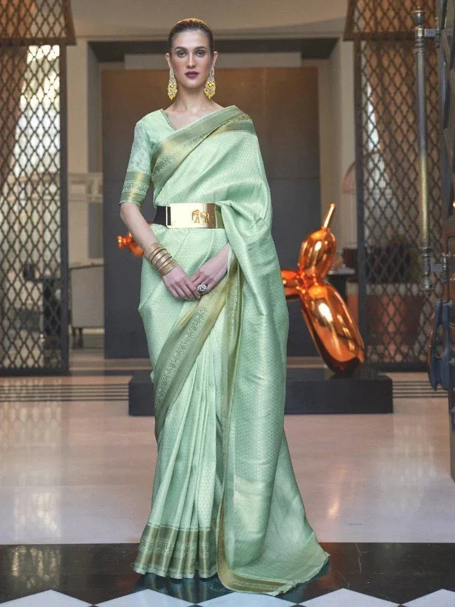 Elegant light green designer saree with gold border, styled with statement belt and jewelry for ethnic occasions