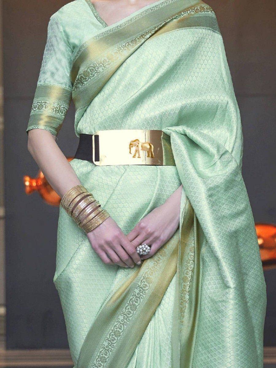 Mint green designer saree with gold border, elephant belt, and bangles for ethnic wear