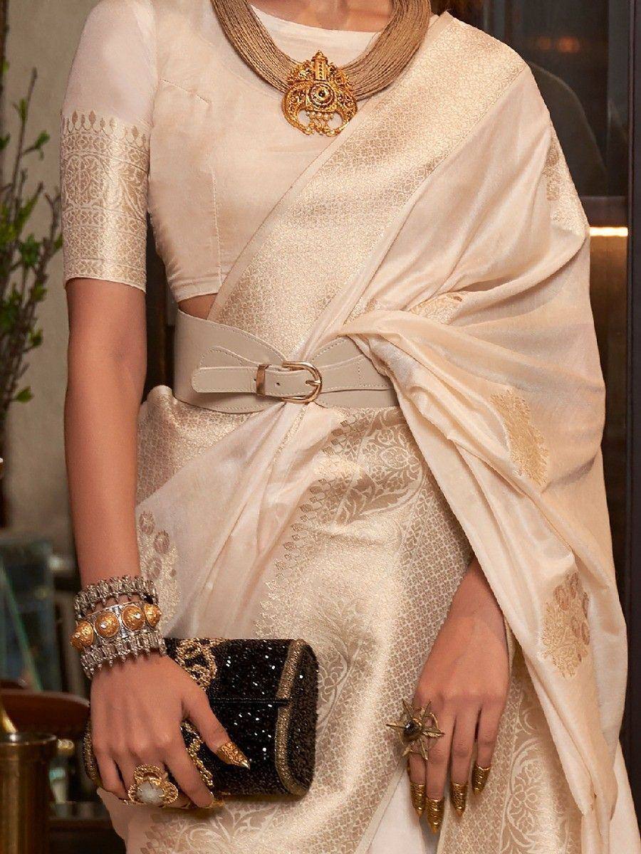 Elegant cream saree with gold embroidery, statement necklace, and designer clutch for Indian ethnic wear