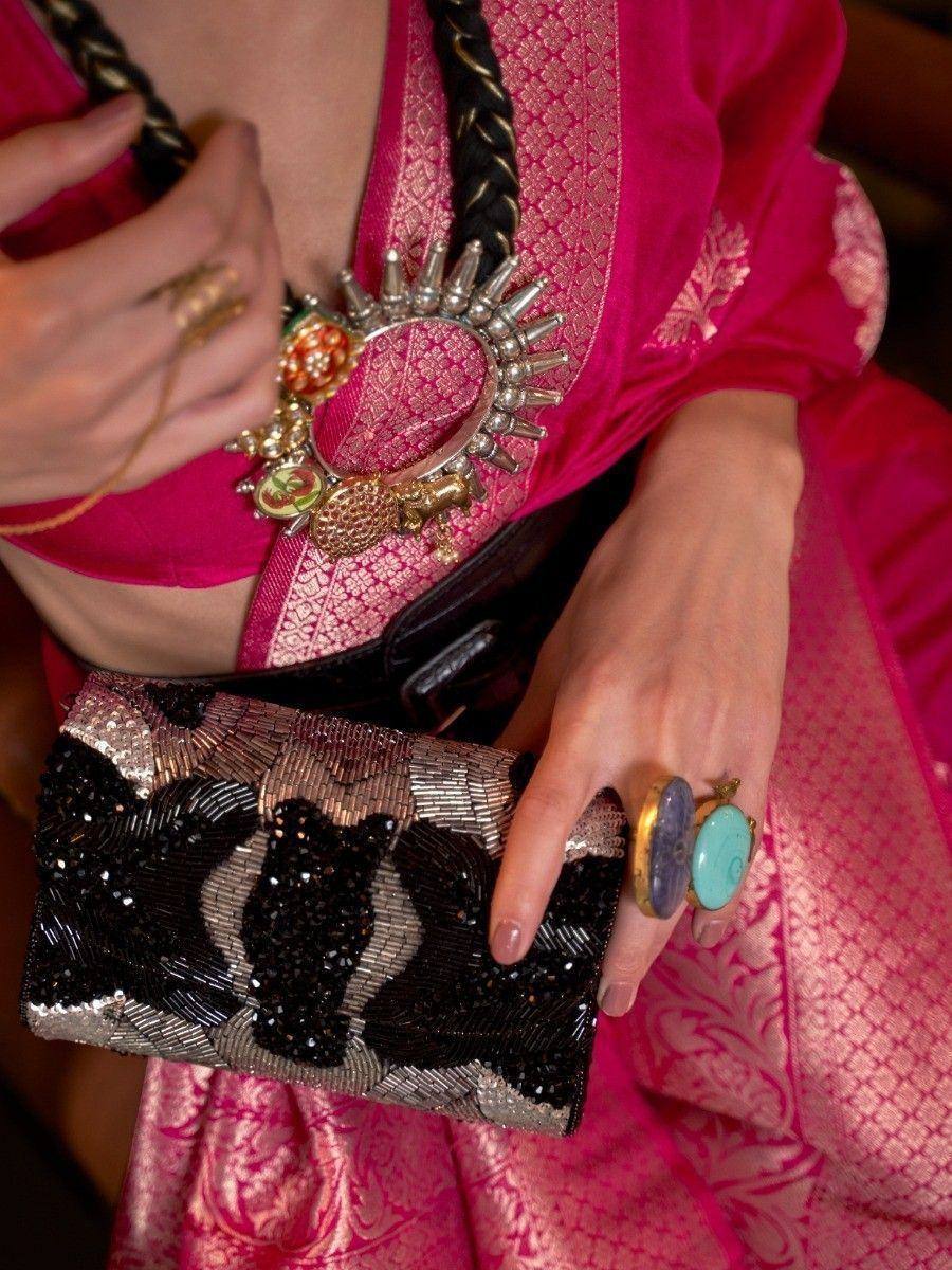 Pink ethnic lehenga choli with gold embroidery, statement necklace, and beaded clutch for Indian weddings