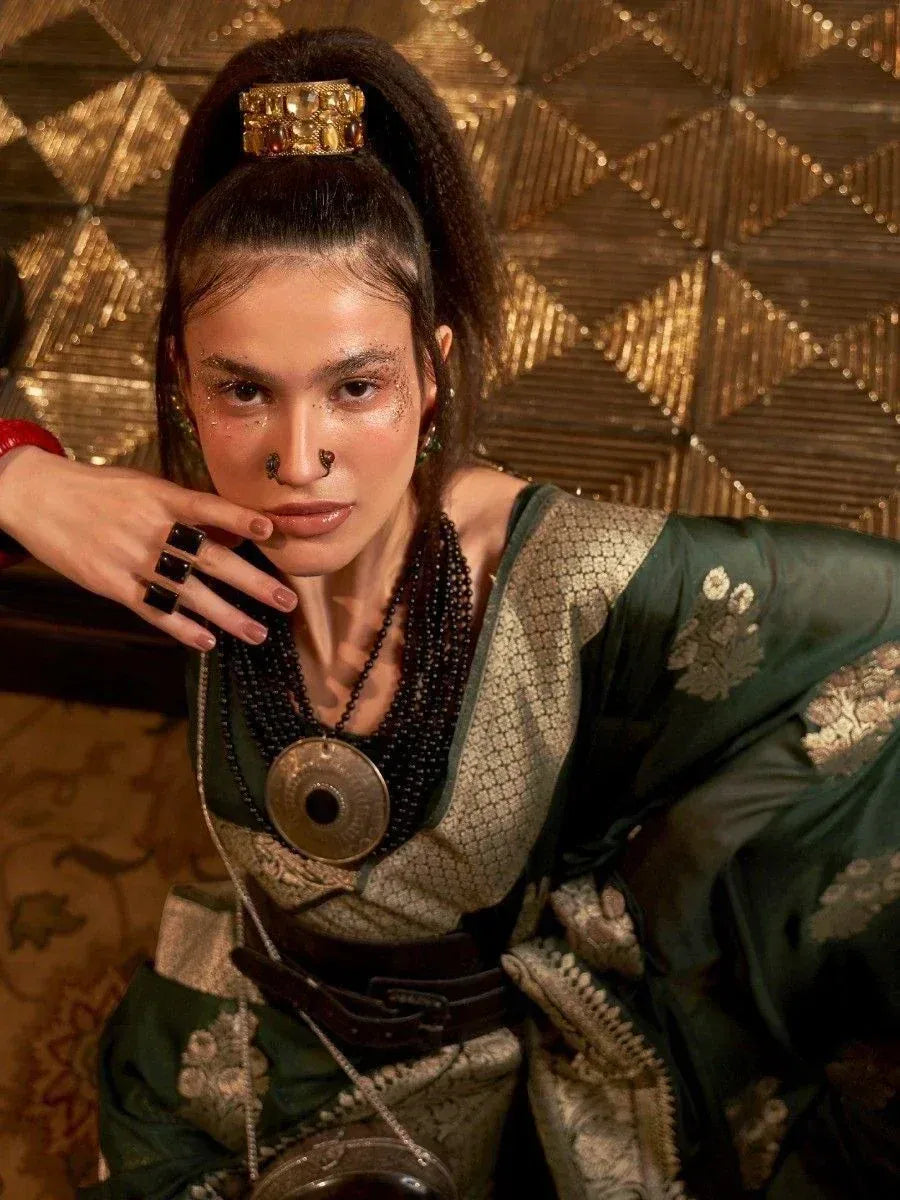 Woman in green ethnic gown with gold embroidery, statement jewelry, and nose ring, styled for festive occasions.