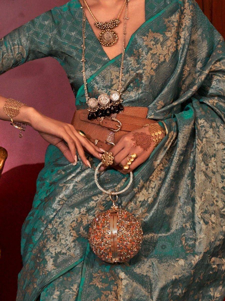 Teal designer saree with gold embroidery, statement jewelry, and embellished clutch for ethnic wear