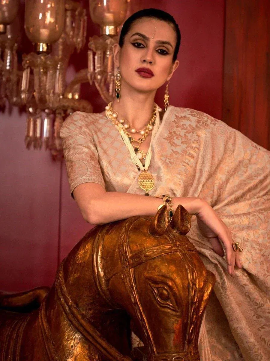 Elegant woman in designer ethnic saree with gold jewelry, posing beside ornate golden horse sculpture