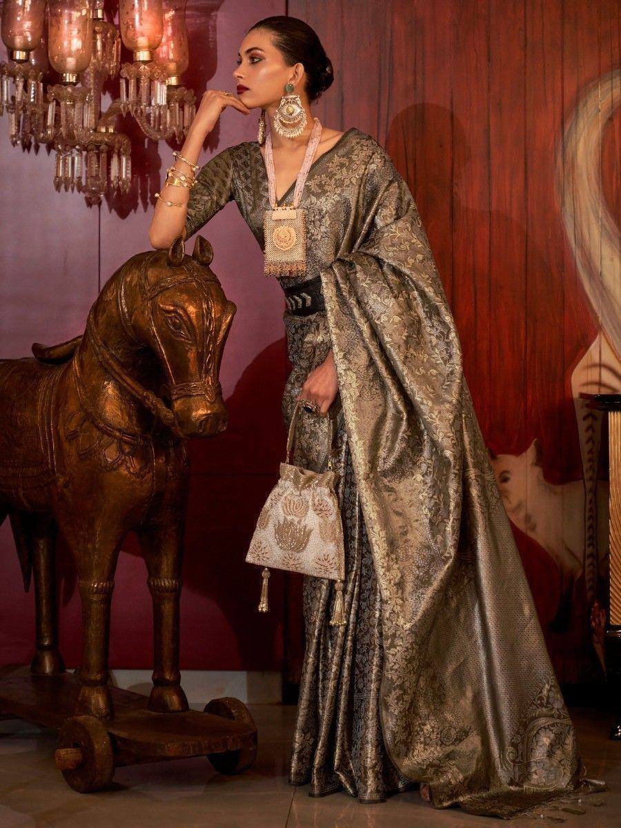 Elegant woman in designer ethnic saree with gold embroidery, paired with statement jewelry and matching potli bag.