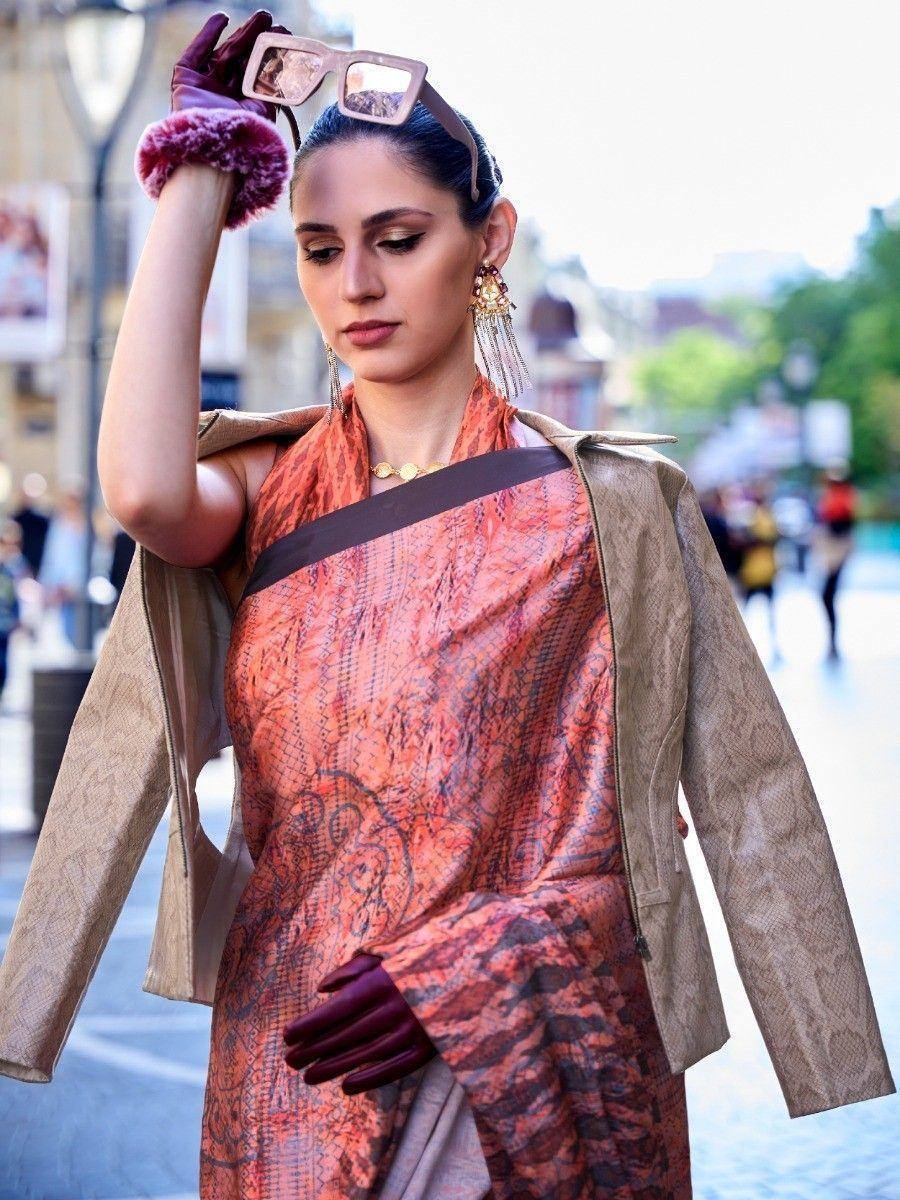 Woman in orange printed saree with snakeskin jacket, statement earrings, and burgundy gloves