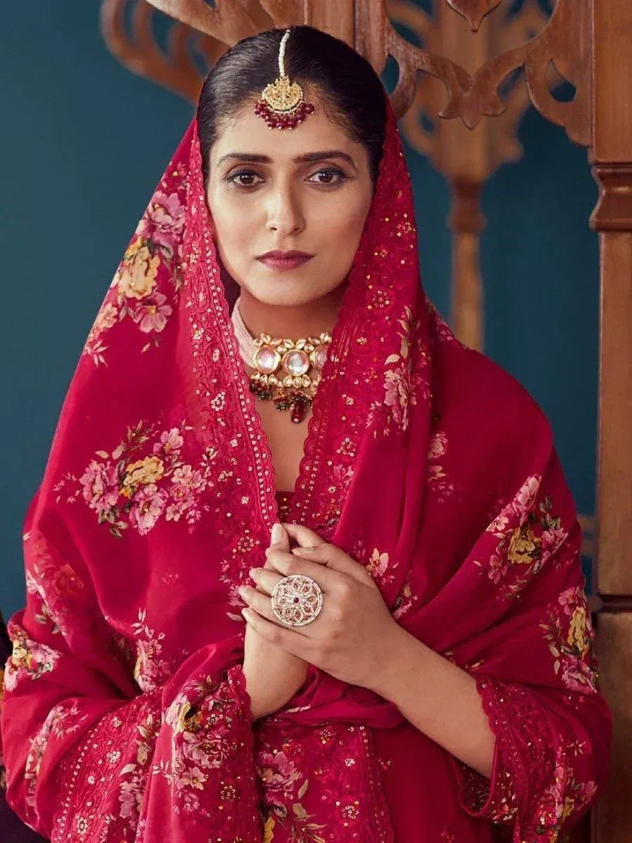 Woman in red floral ethnic outfit with traditional jewelry and dupatta, perfect for Indian weddings or festivals.