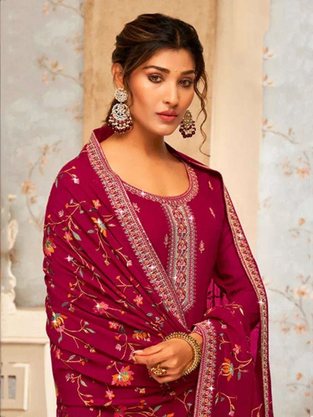 Woman wearing maroon embroidered salwar kameez with floral dupatta and statement earrings