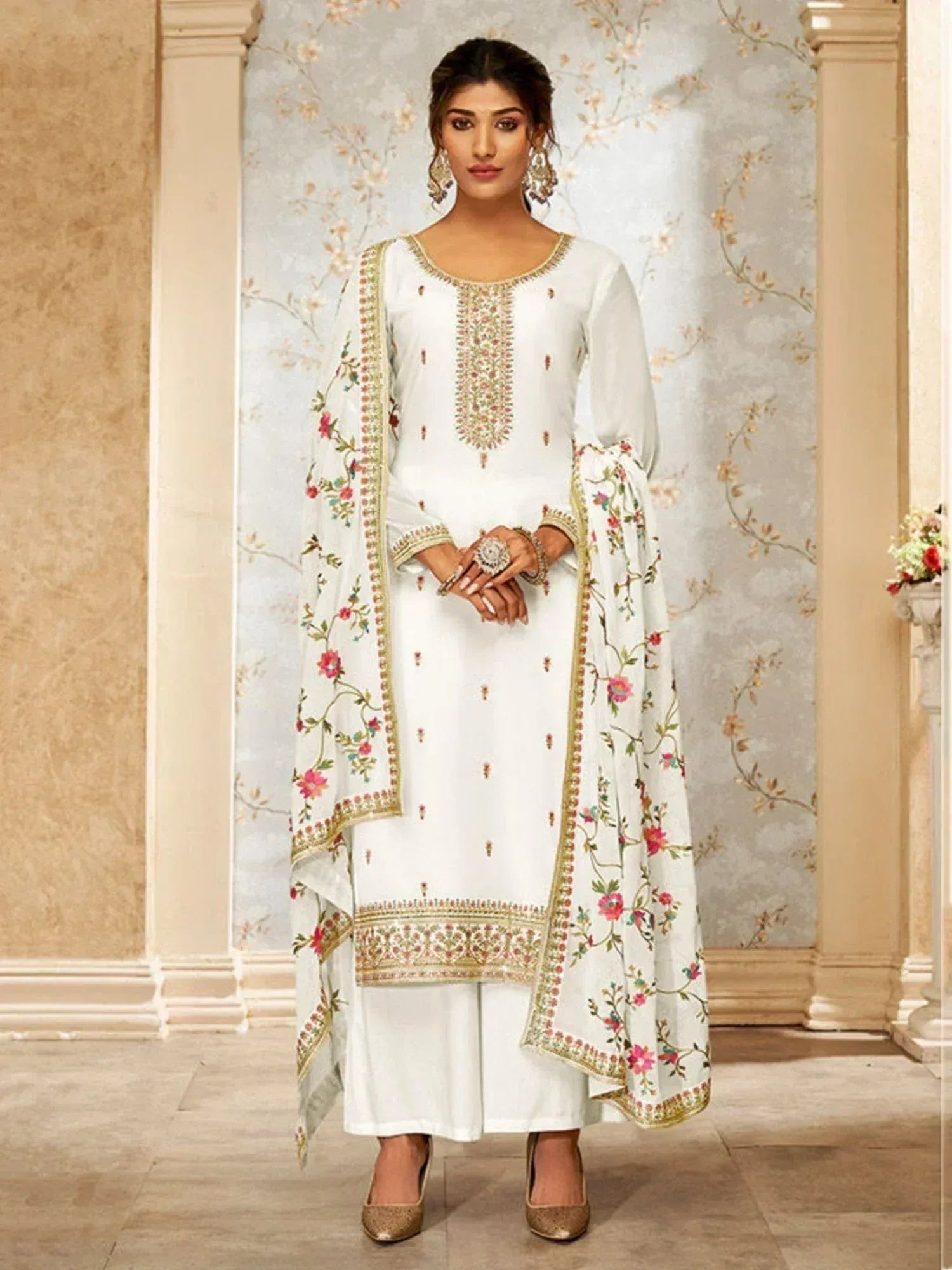 Woman in white embroidered salwar kameez with floral dupatta and gold accents