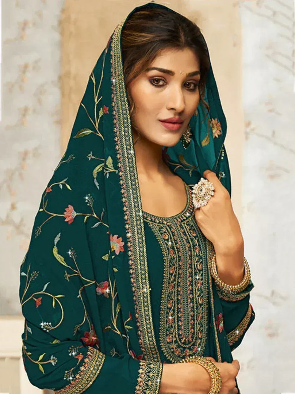 Woman wearing green embroidered salwar kameez with floral dupatta and gold jewelry