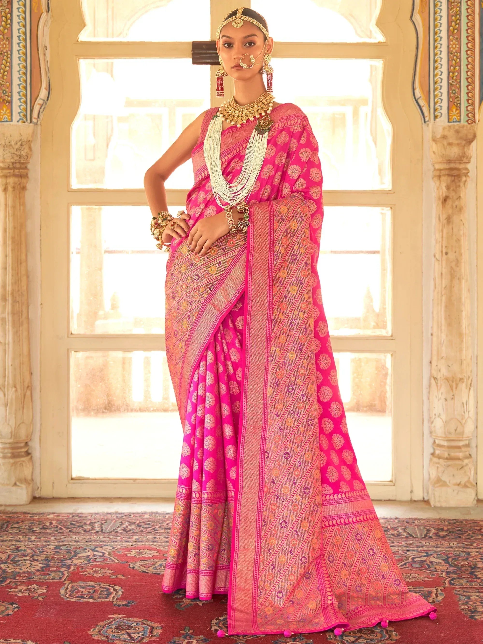 Vibrant pink ethnic saree with intricate gold patterns, traditional jewelry, and palace backdrop