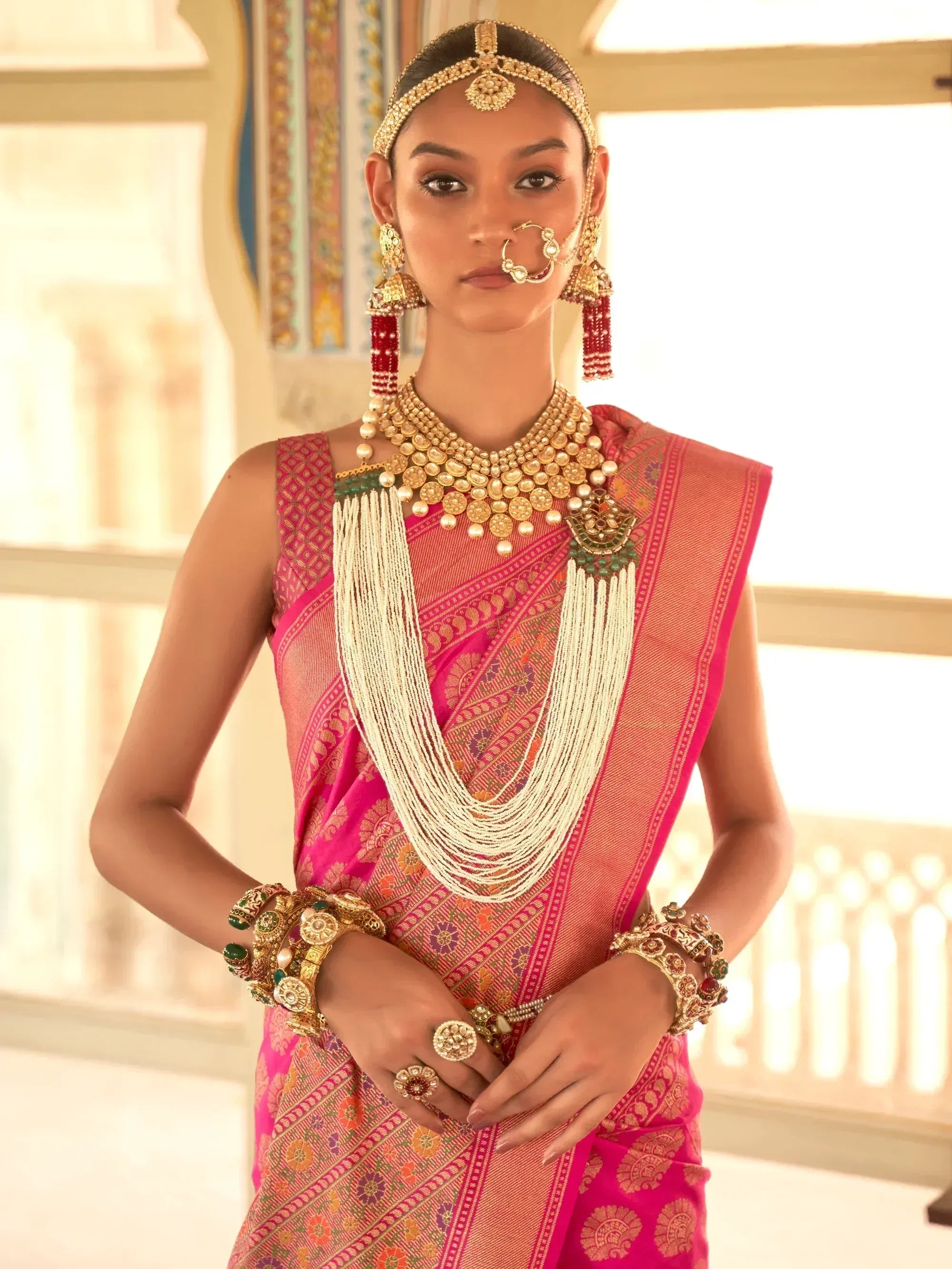 Woman in vibrant pink ethnic saree with gold jewelry, perfect for Indian weddings or festivals