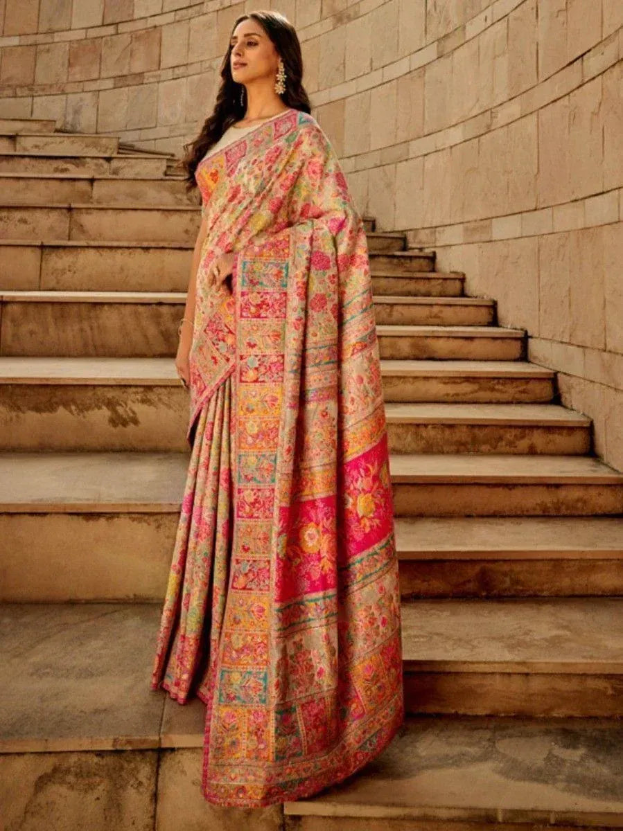 Woman in vibrant floral printed saree with intricate border, standing on stone steps