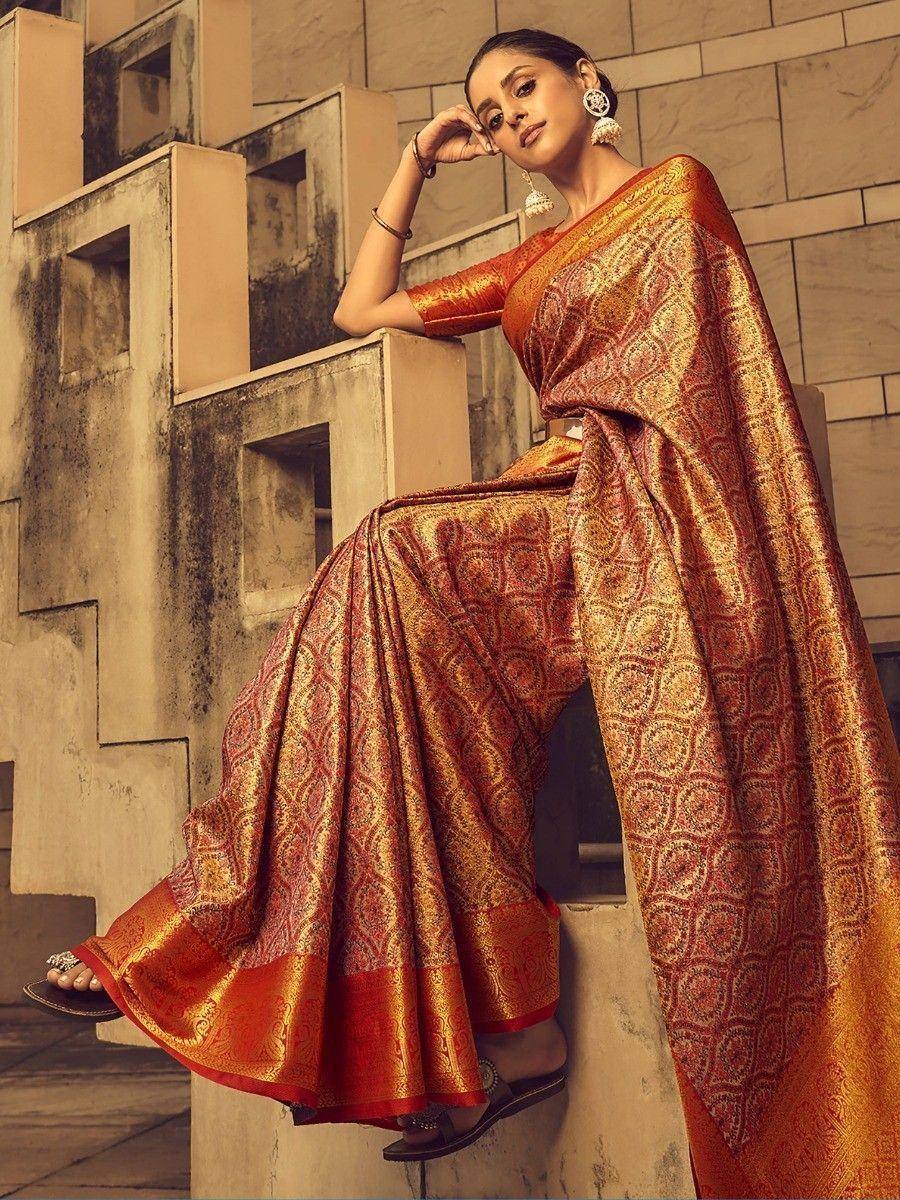Elegant woman in designer orange and gold saree with intricate patterns, perfect for Indian ethnic wear occasions.