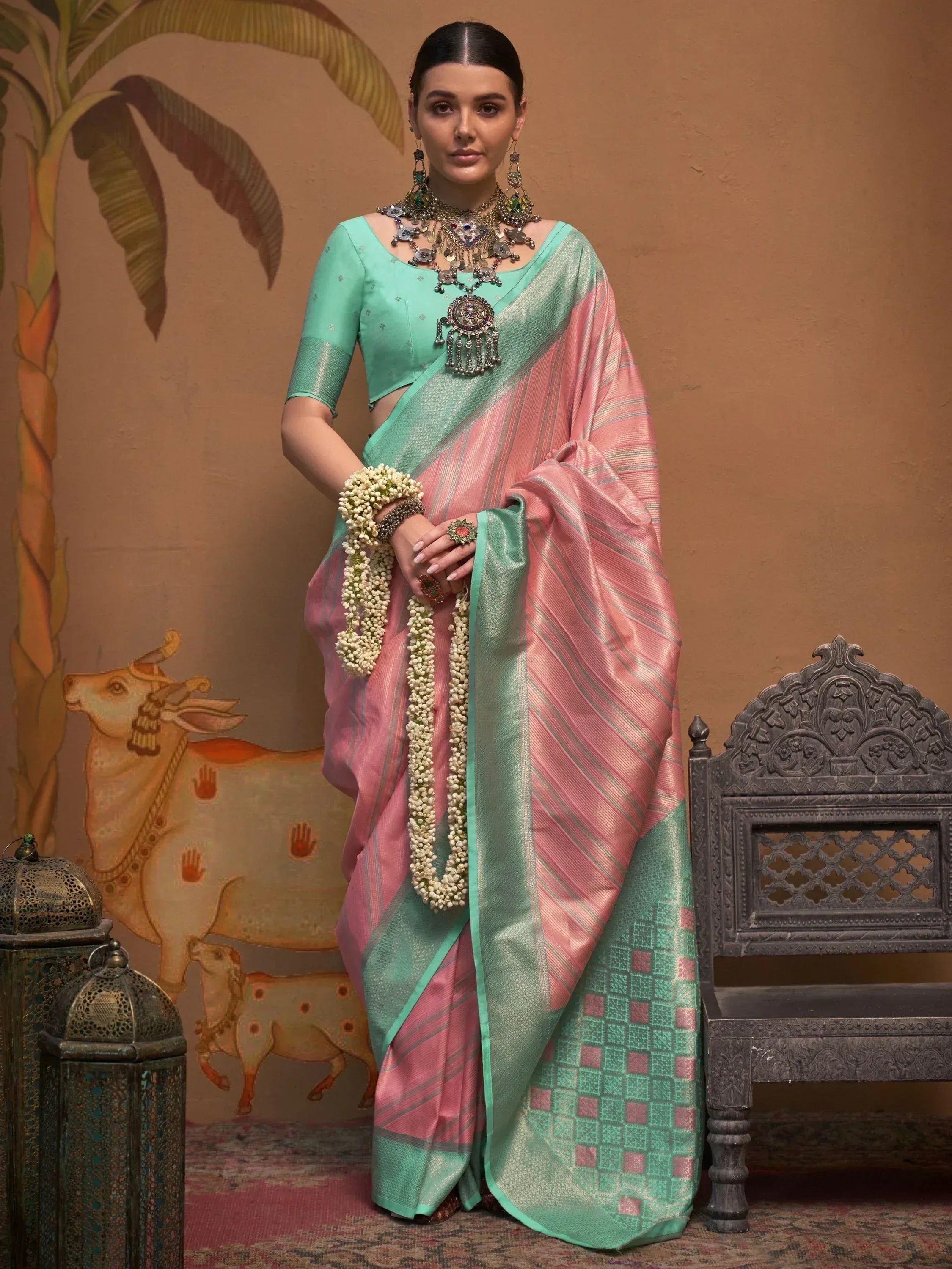 Woman in pink and mint green silk saree with traditional jewelry, perfect for Indian ethnic wear occasions.