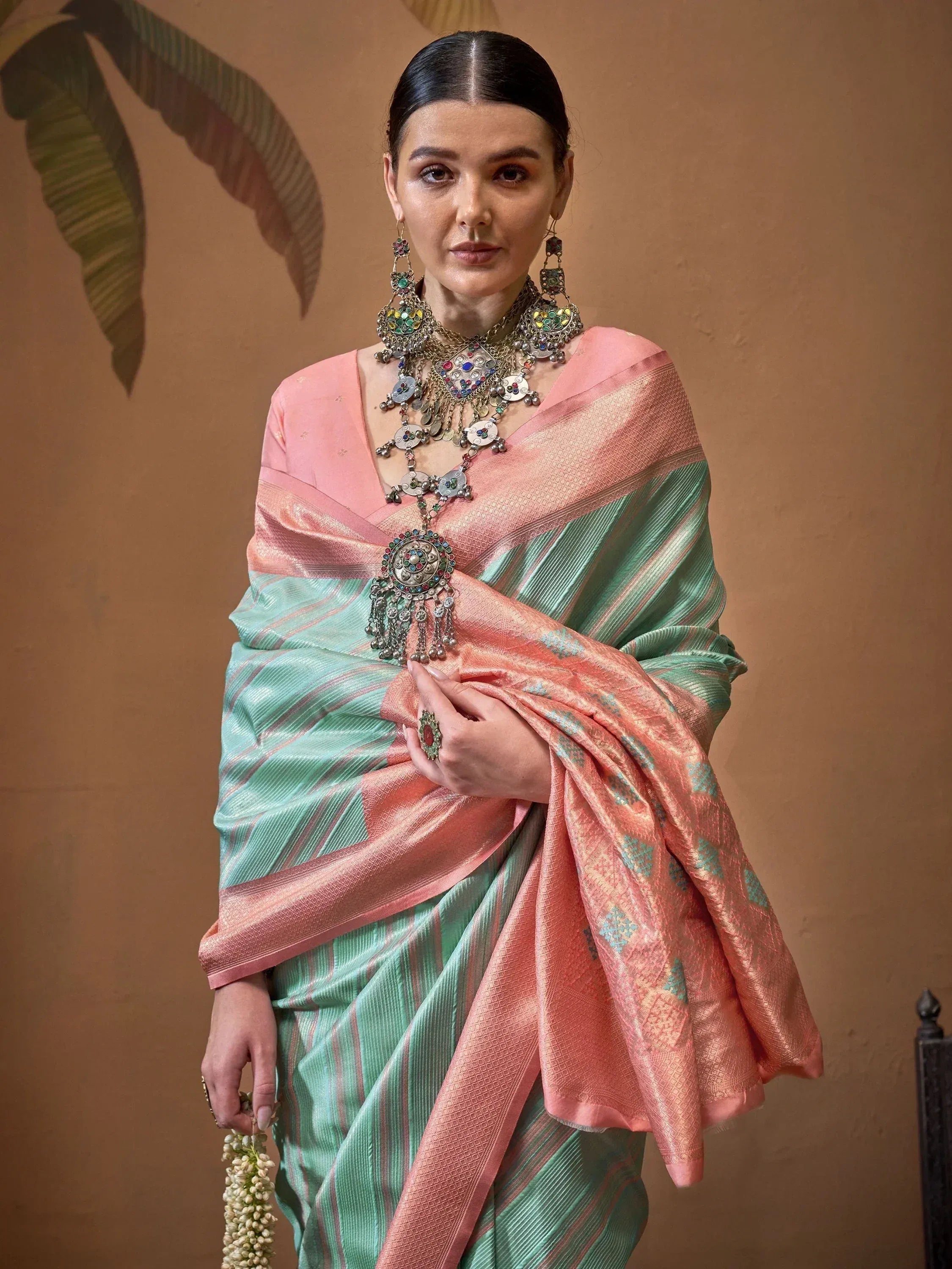 Woman in pink and mint green designer saree with ethnic jewelry, perfect for Indian ethnic wear occasions