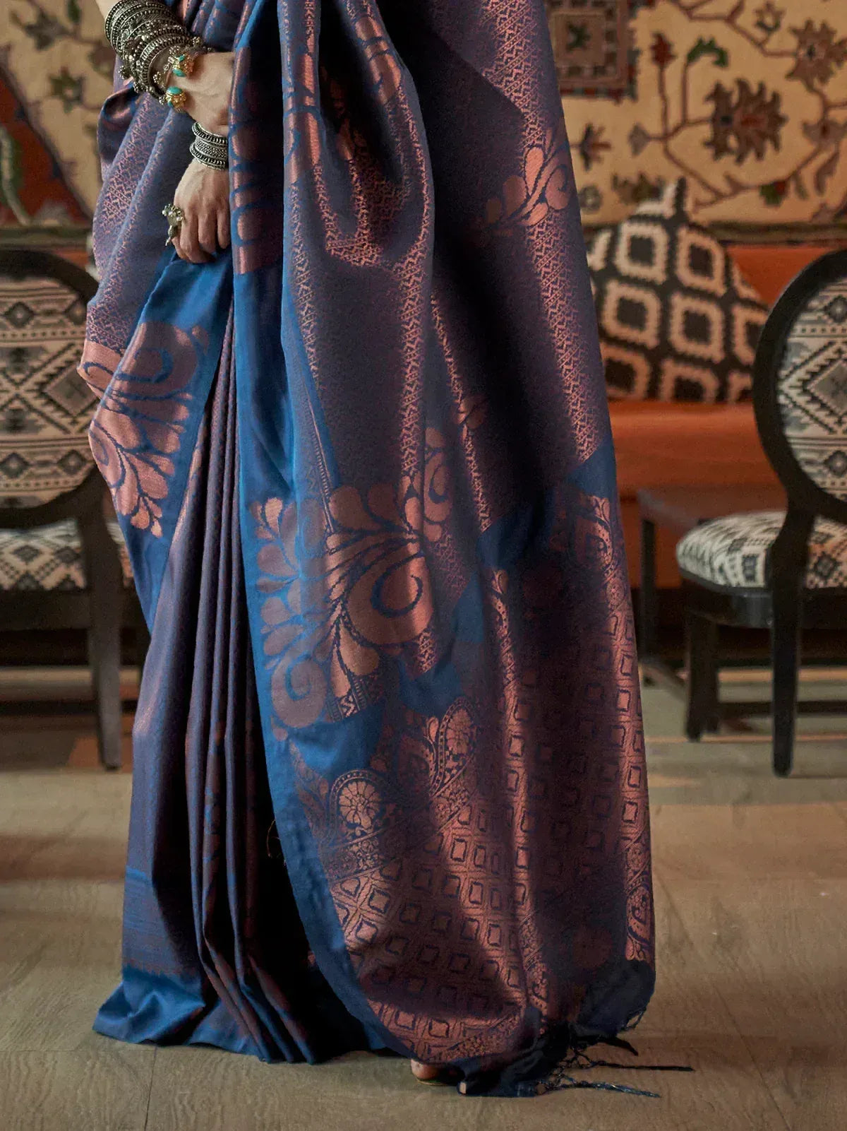 Blue and copper designer saree with intricate floral and geometric patterns, styled with traditional bangles.