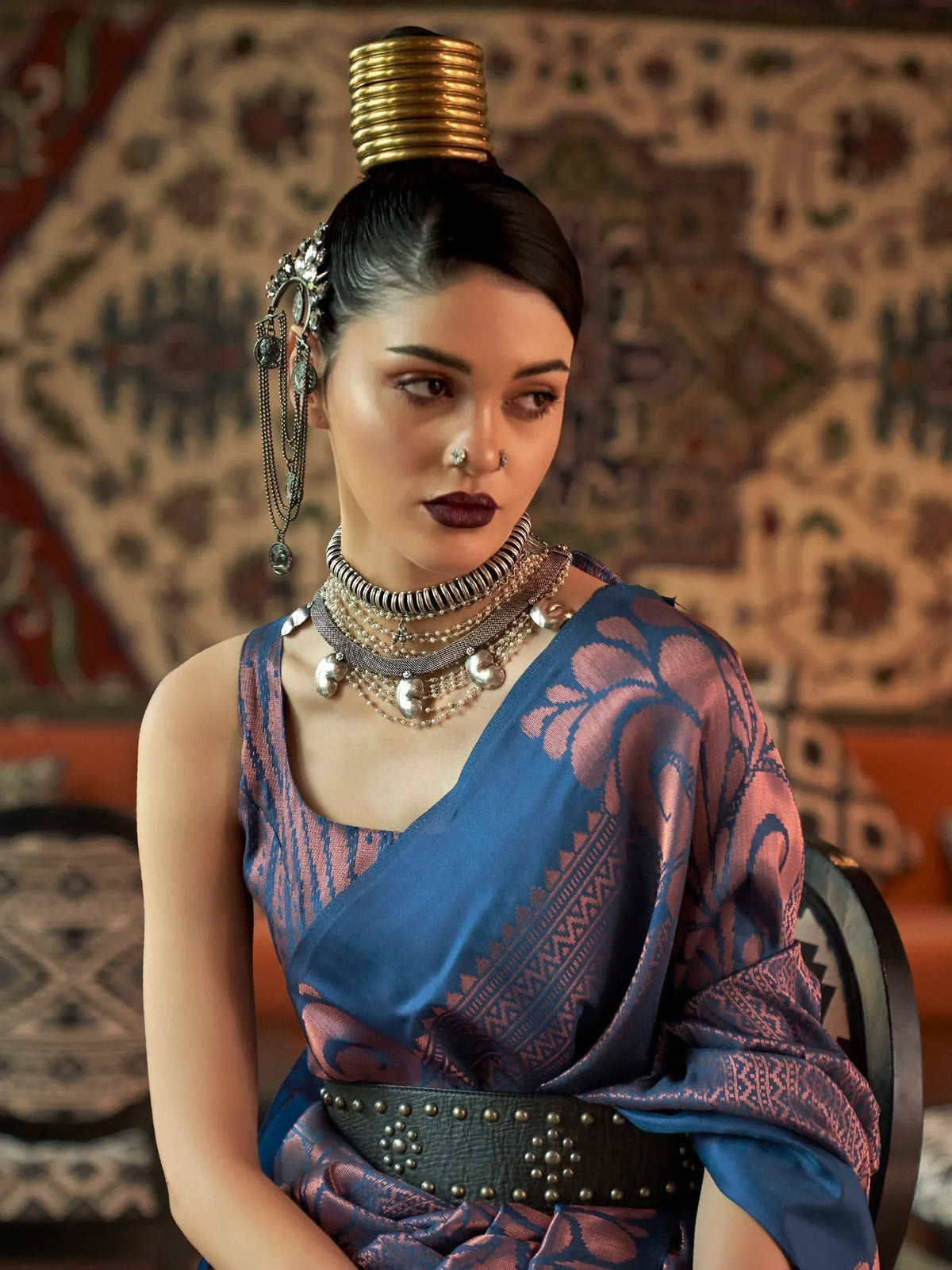 Woman in blue and pink ethnic saree with gold headpiece and silver jewelry, traditional Indian wear