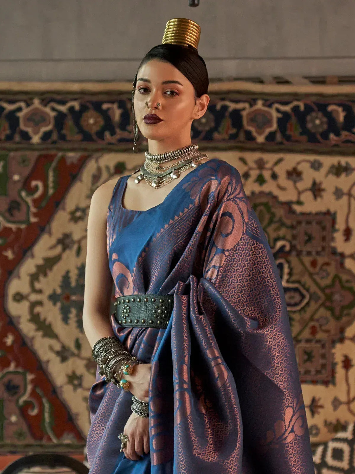 Woman in blue and gold ethnic saree with traditional jewelry and ornate headpiece, styled for festive occasions.