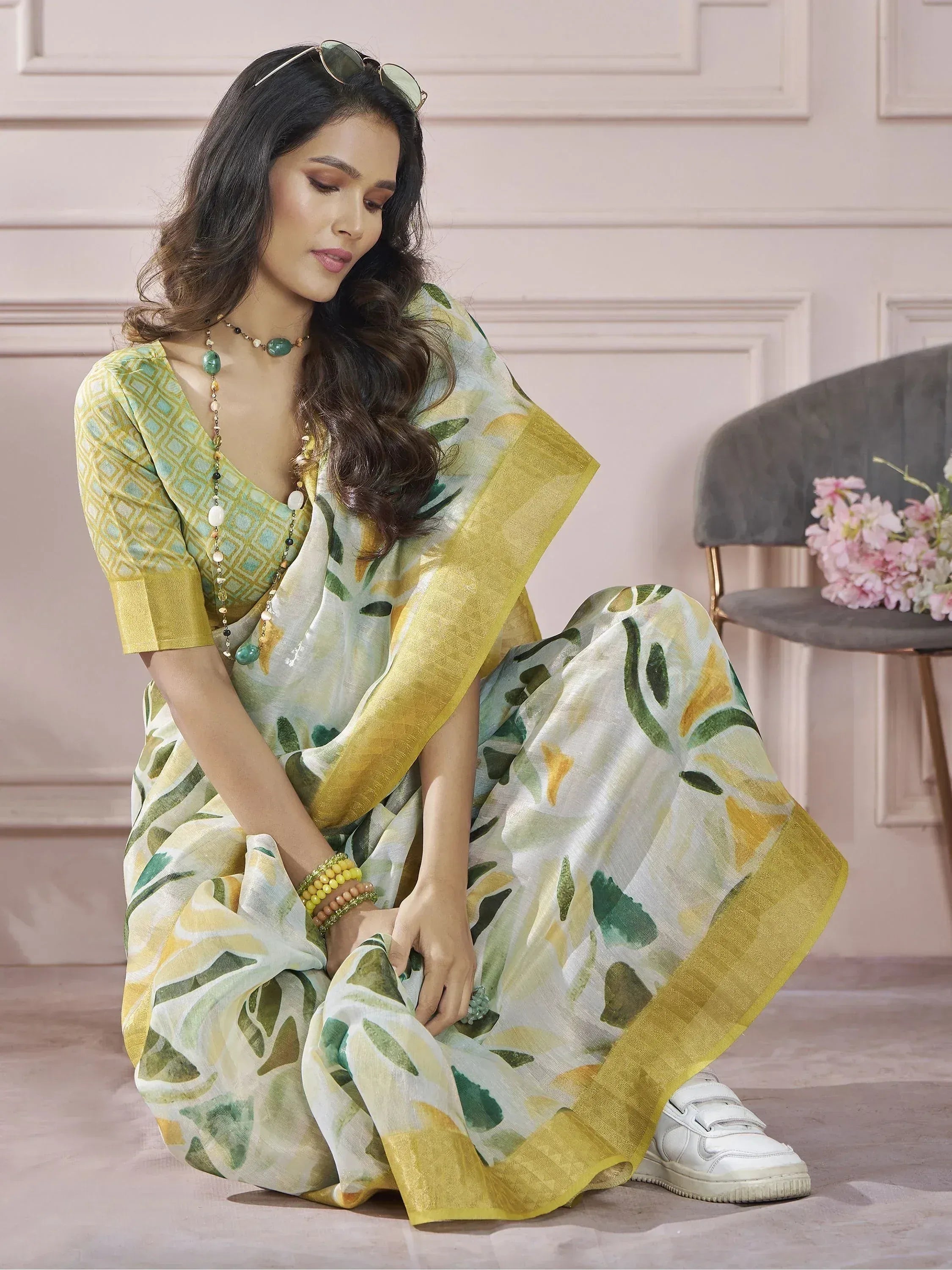 Woman in floral print saree with yellow border, paired with ethnic blouse and white sneakers