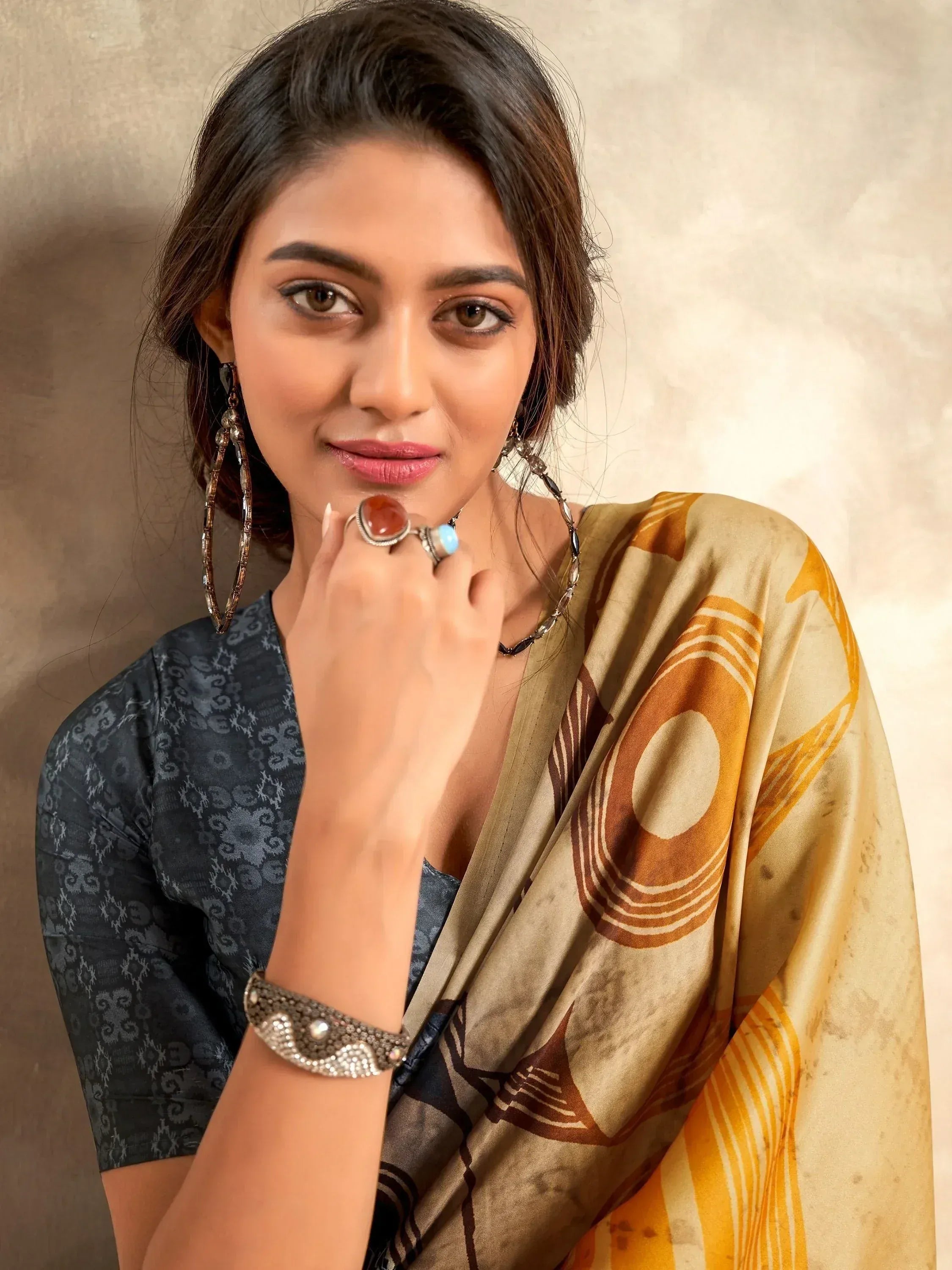 Woman in stylish Indian saree with geometric print, paired with statement jewelry and blouse.