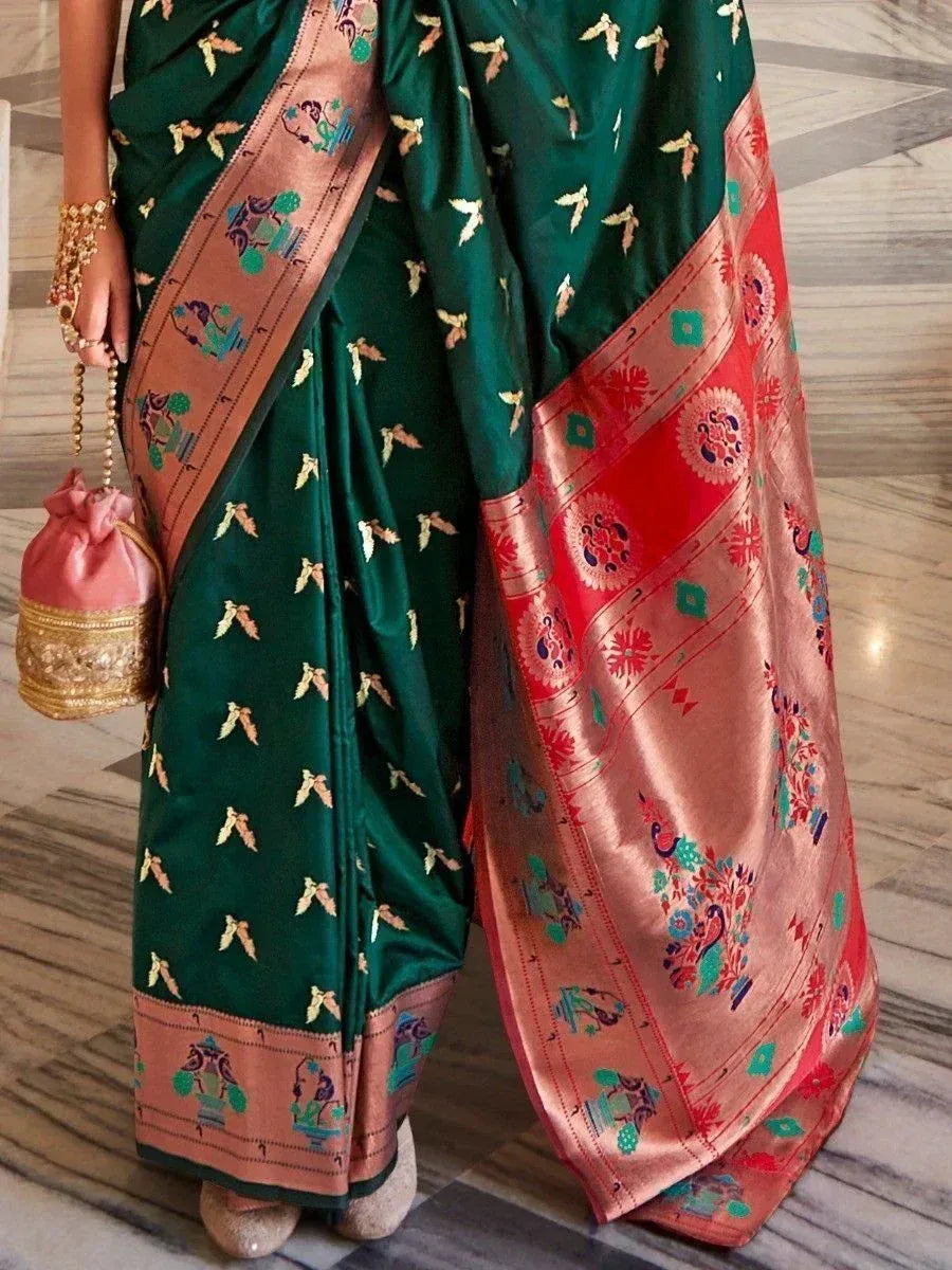 Emerald green saree with gold motifs and colorful peacock border, paired with pink potli bag for Indian ethnic wear