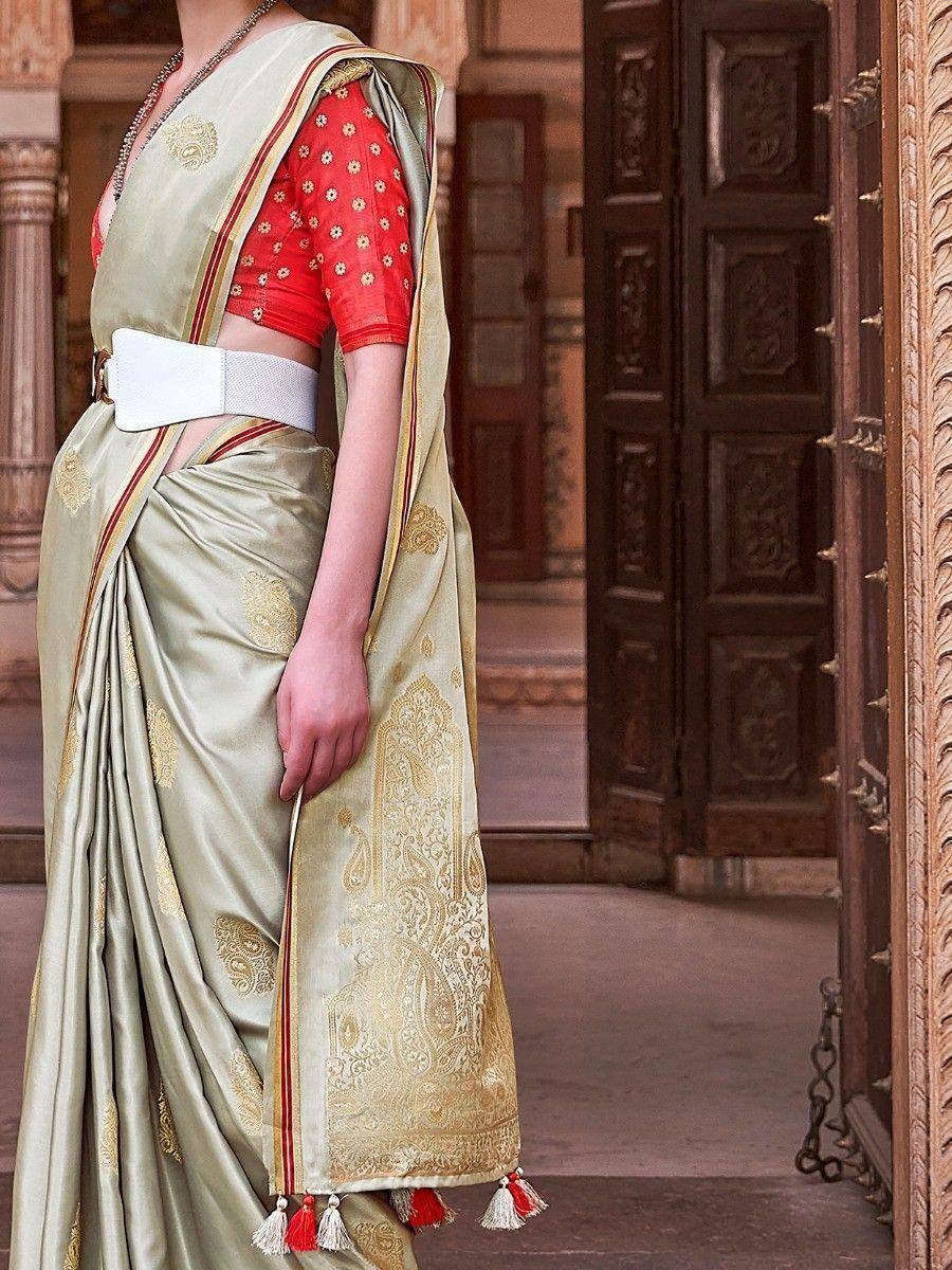 Elegant olive green saree with gold paisley print, red blouse, and tassels, styled with white belt for Indian ethnic wear.