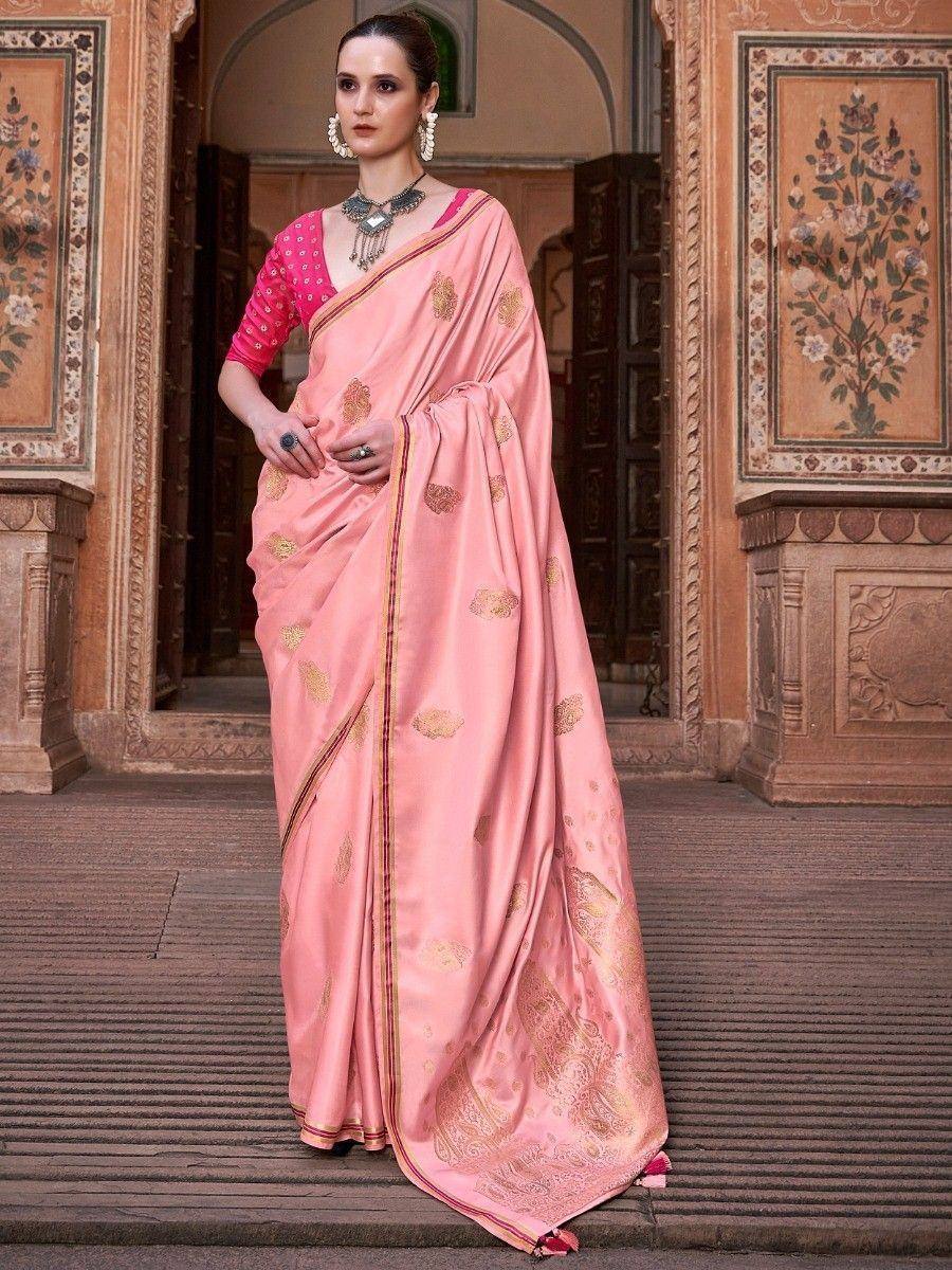 Pink embroidered saree with gold motifs, paired with pink blouse, worn by woman in traditional Indian setting